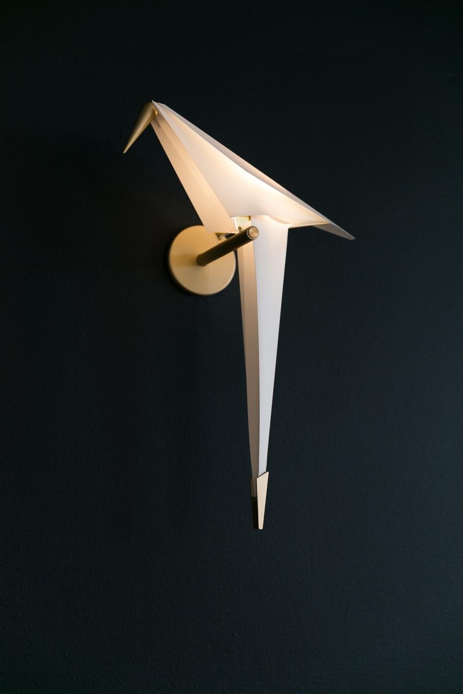 Made of folded paper and brass, the Perch evokes a feeling of freedom. Let the graceful bird swing and glow with joy. Just beware that it might just spread its wings and fly away… This sunlit bird is free to swing when softly touched. It gently