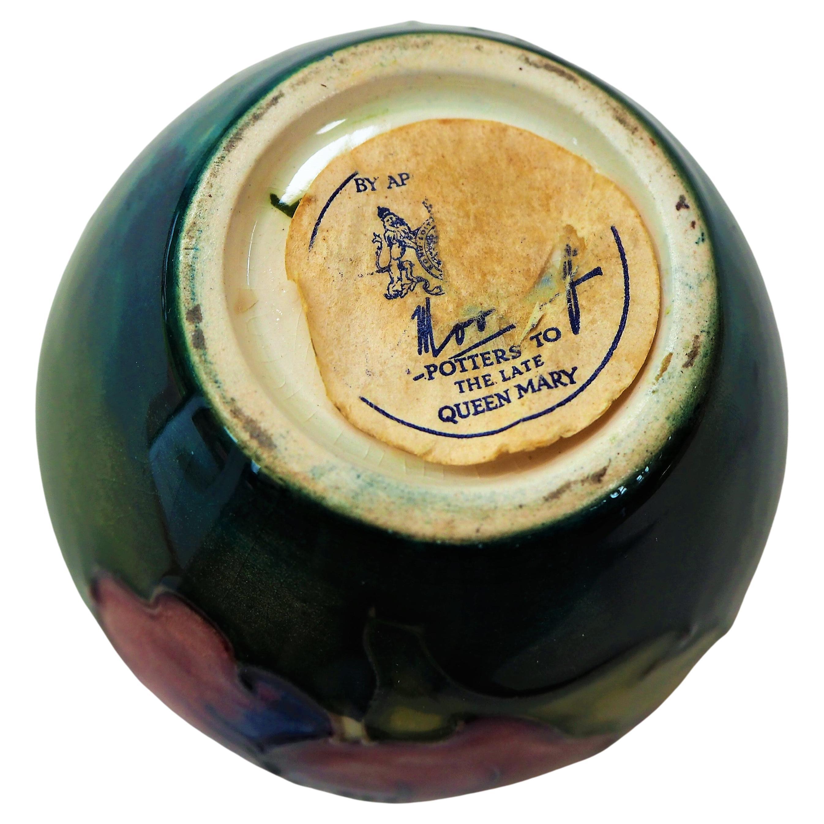 This quaint Mooorcroft Vase has a hibiscus design in both yellow and red upon a forest green background. One of the rarer handmade pieces as it has the royal paper seal appointing Moorcroft as potter 