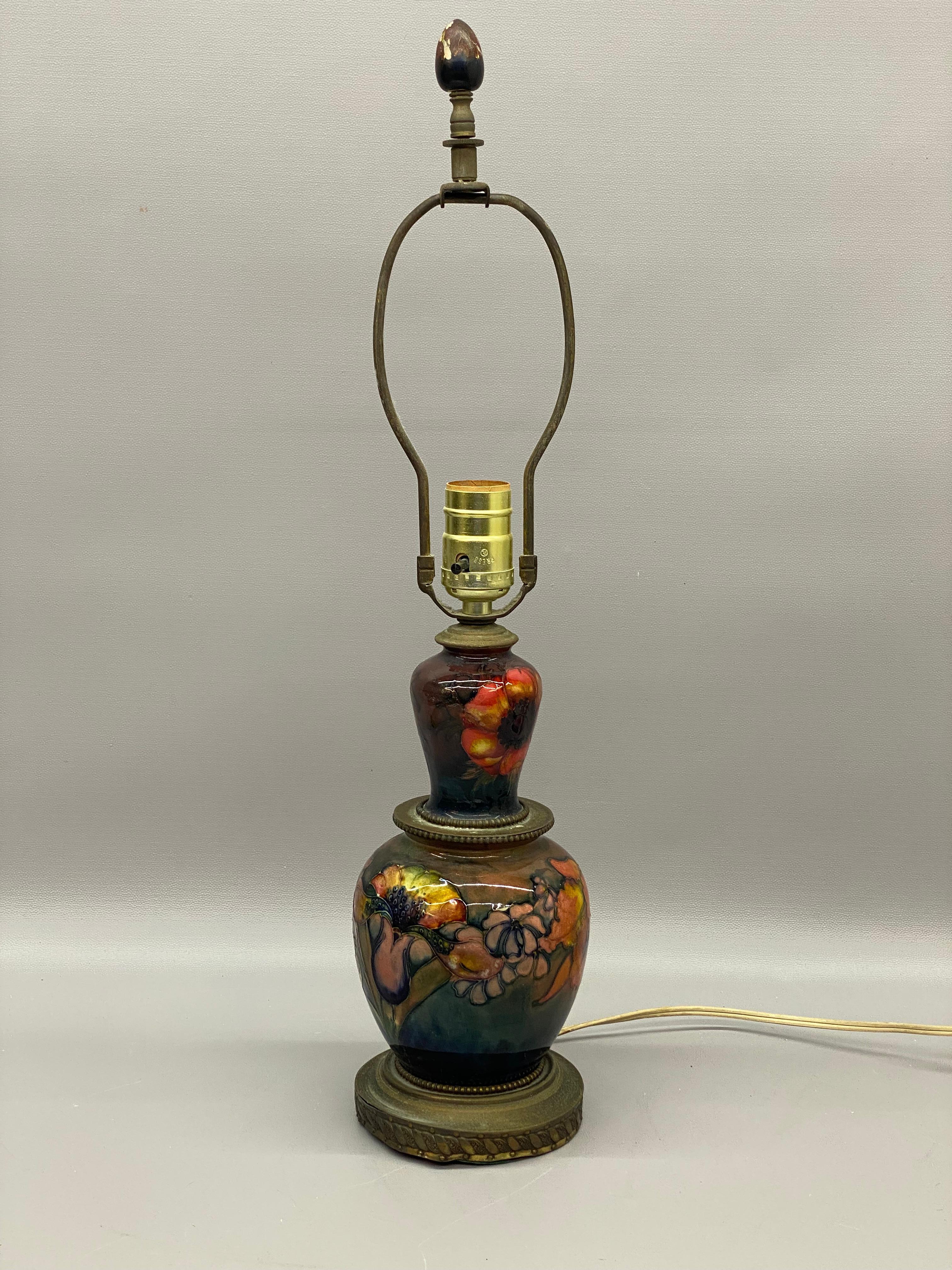 Beautifully hand decorated and colorful Moorcroft Pottery table lamp. Decorated with lilies, poppies and other flora. Moorcroft pottery, known for its vibrant, hand-painted designs, has a rich history rooted in the English Arts and Crafts movement.