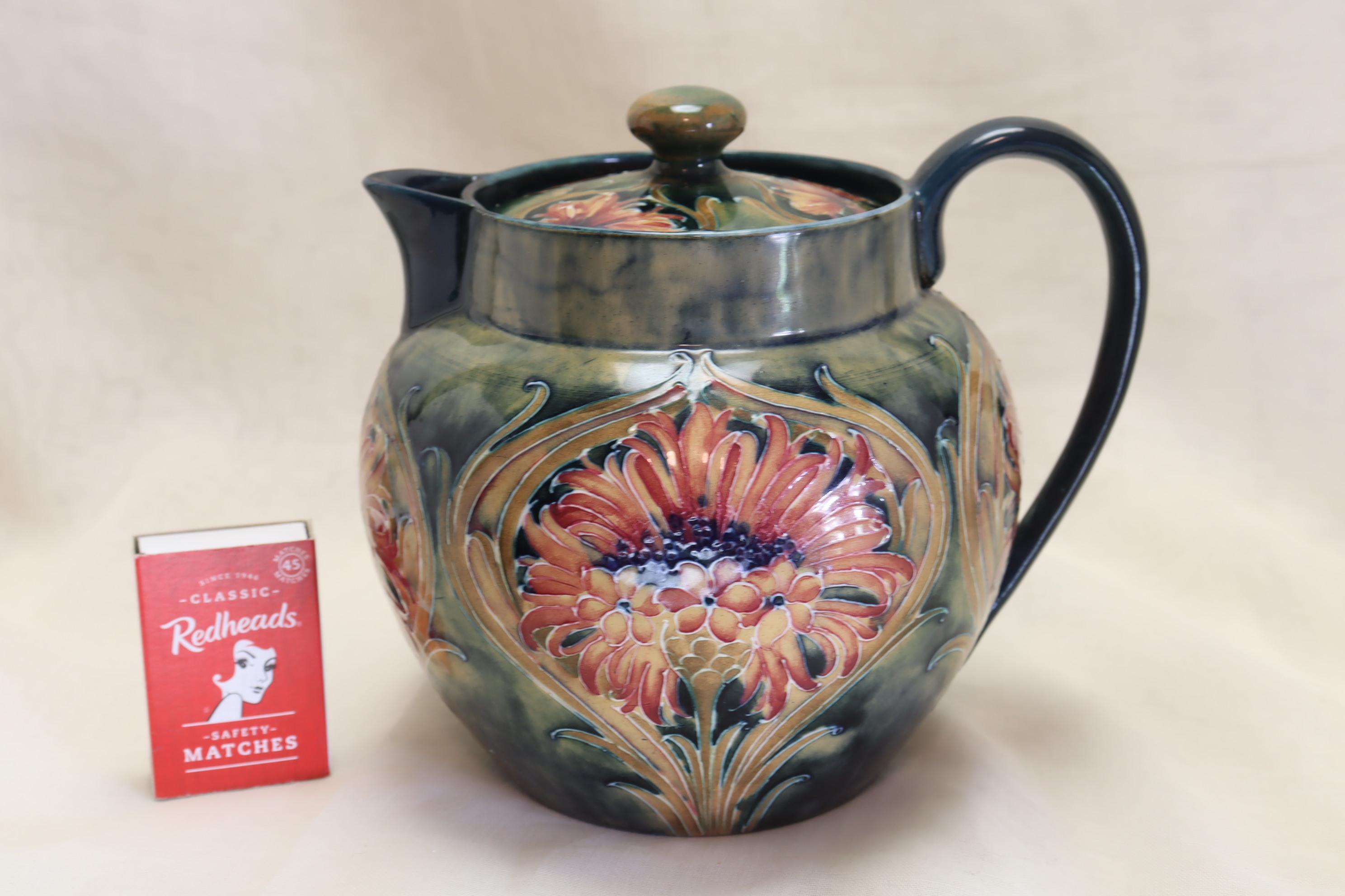 This Moorcroft teapot is decorated with the Revived Cornflower, or Brown Chrysanthemum design on a mottled green ground. This design was introduced in 1910-12 while William Moorcroft was still at McIntyre's, and it continued in use after he set up