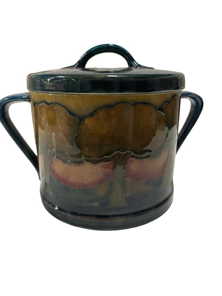 A twin-handled cylindrical biscuit barrel and cover decorated in the 'Eventide' pattern, in shades of ochre, rose, and petrol blue, impressed factory marks, signed in blue.
Glazed earthenware .

14cm high (5.5 inches), 18.5cm (7.2 inches