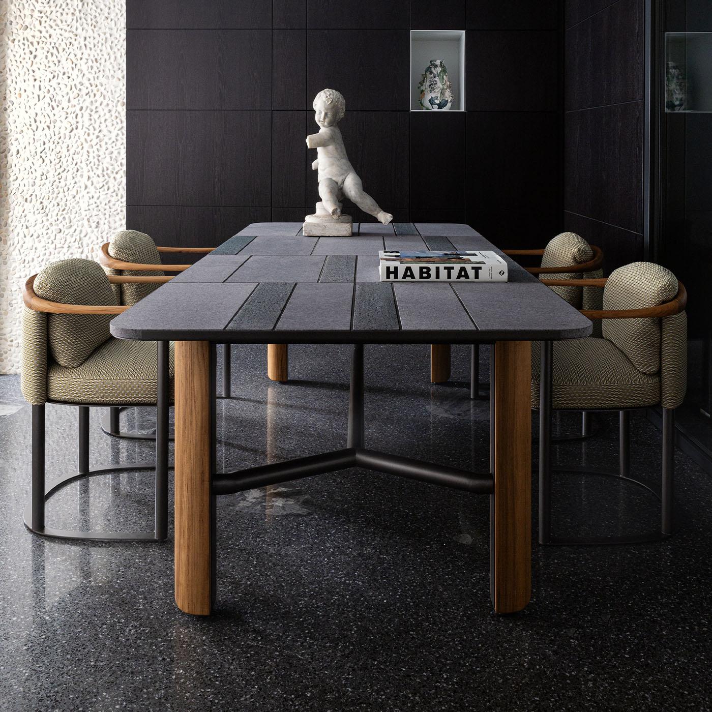 La sedia Moorea presenta una struttura in acciaio inossidabile verniciato color peltro abbinata a braccioli e schienale in legno massiccio di teak. Progettato per l'uso all'aperto, include un'imbottitura in gomma drenante che resiste all'umidità e