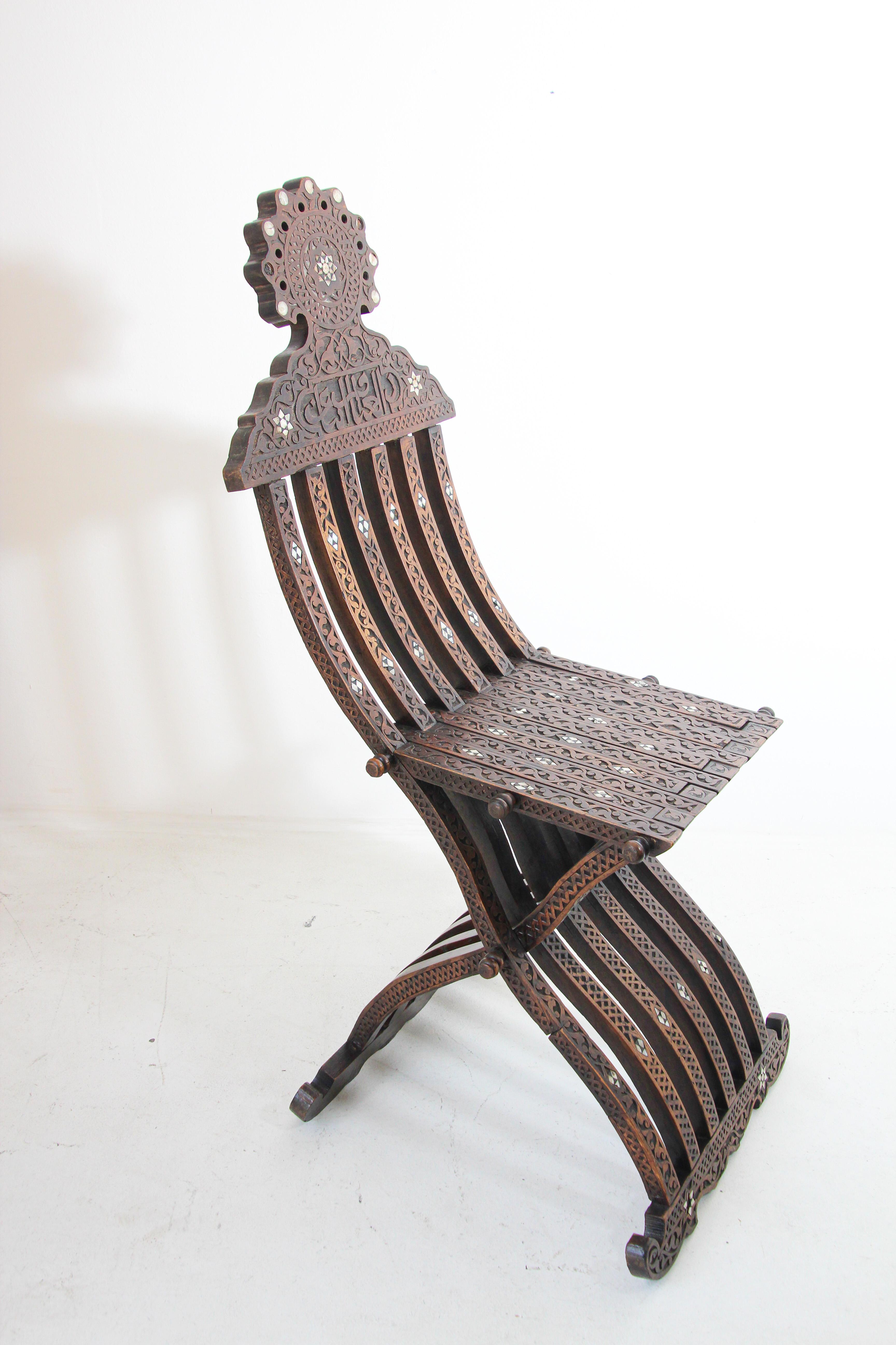 Antique Middle Eastern Egyptian Moorish walnut wood folding chair with intricate foliate carving and mother of pearl, shell inlays.
Arabian Syrian style folding chair inlaid with mother of pearl stars designs, hand carved with Arabic calligraphy
