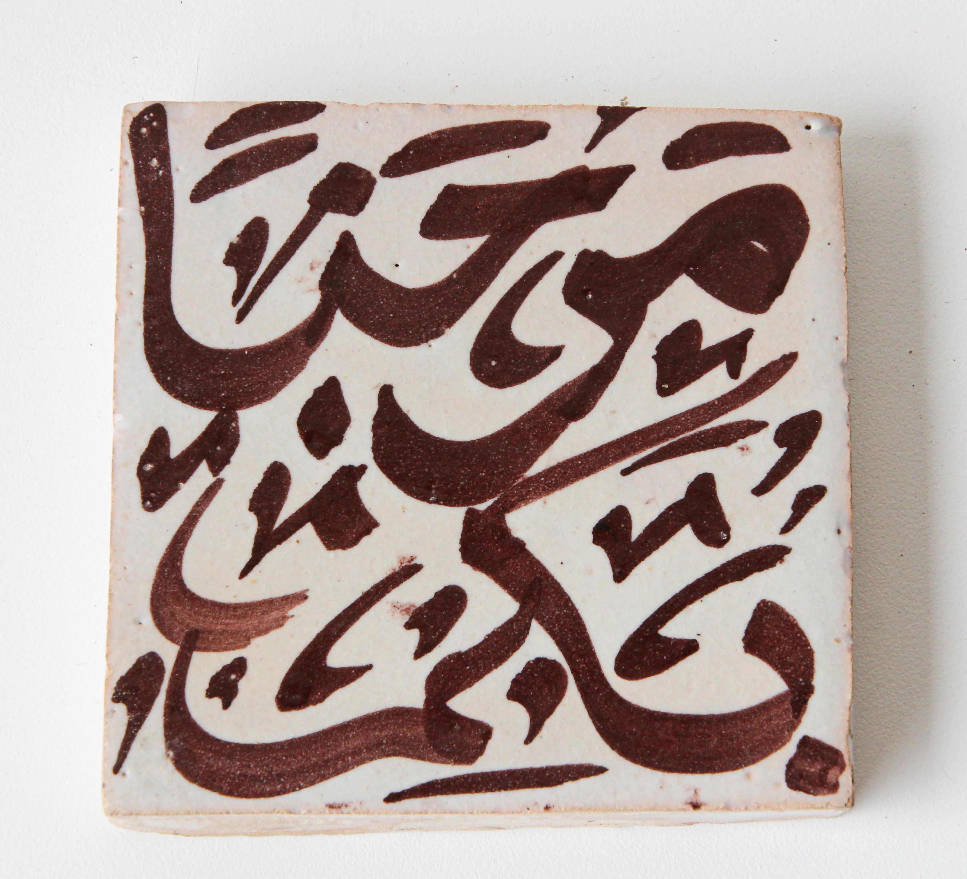 Carreau décoratif marocain artisanal avec écriture arabe peinte à la main en brun sur céramique ivoire émaillée craquelée.
Écriture arabe sur un carreau de céramique peint à la main par un artiste de Fès, au Maroc.
Grand zellige décoratif d'art