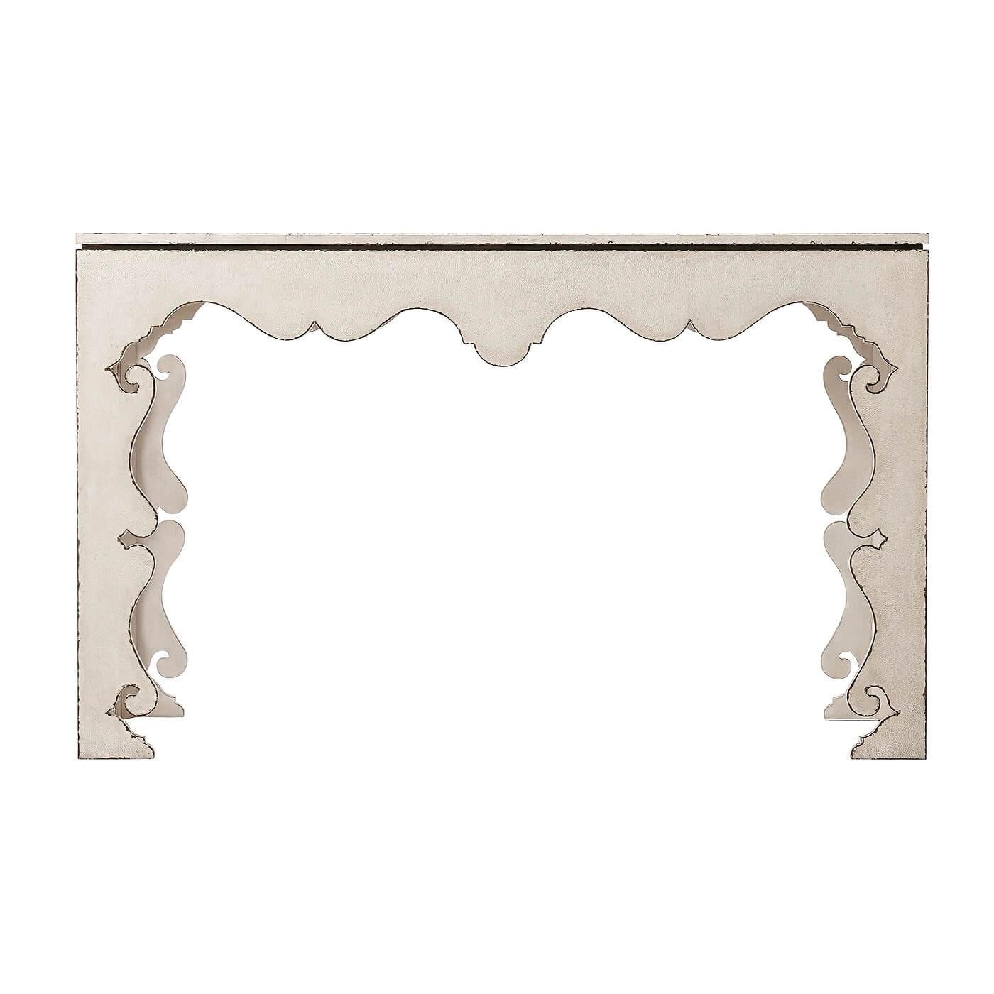 A Moorish influenced vintage cream painted console table, the rectangular floating and leather strapwork relief decorated top, on square exterior edge legs with serpentine fretwork interiors.

Dimensions: 58