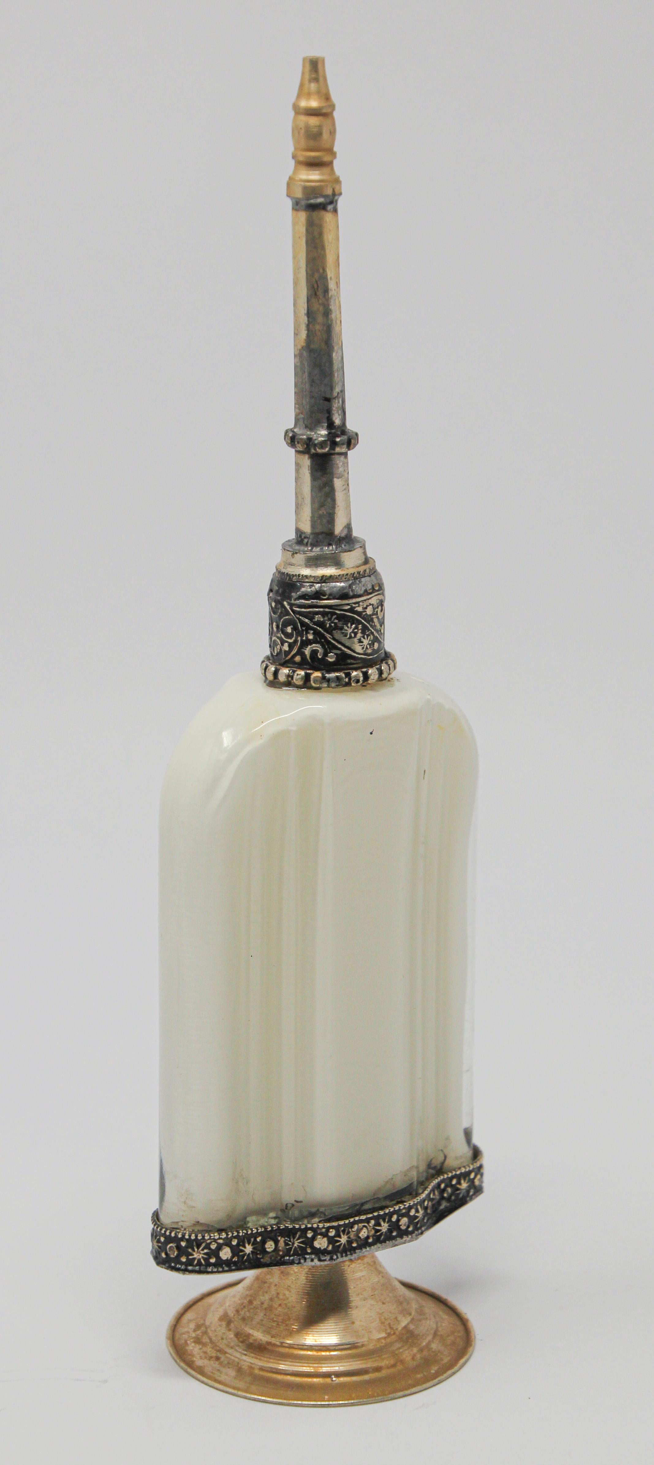 Handcrafted Moroccan Moorish white glass perfume footed bottle or rose water sprinkler with raised embossed silvered metal floral design over glass.
The pressed glass bottle in Art Deco, Art Nouveau style is oval shape with curved sides and hand