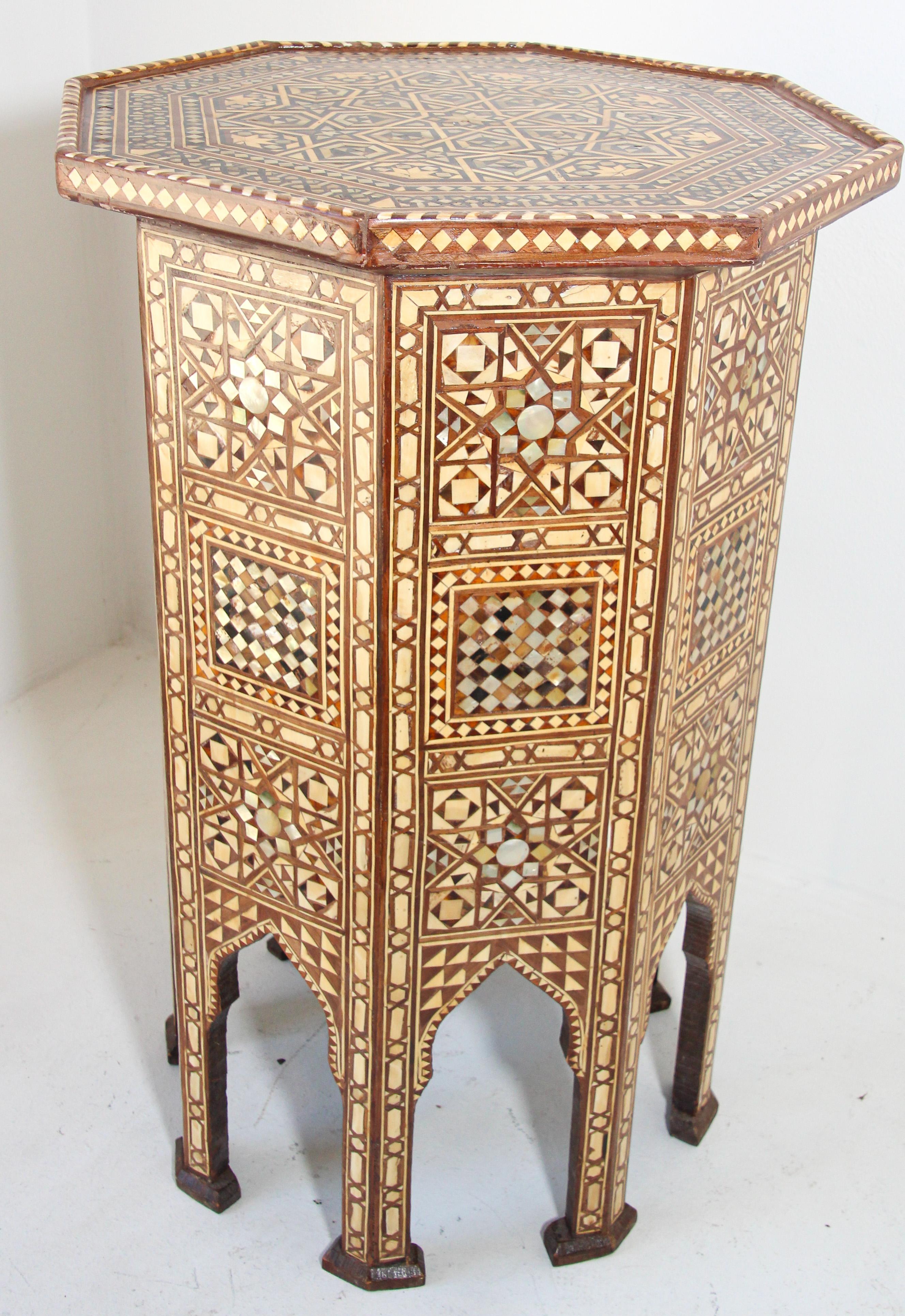 Guéridon octogonal en noyer de style mauresque marocain, incrusté de mosaïques.
Le plateau de la table est de forme octogonale, décoré de divers motifs géométriques et d'arabesques.
La table repose sur huit pieds séparés par des arcs cuspidés et