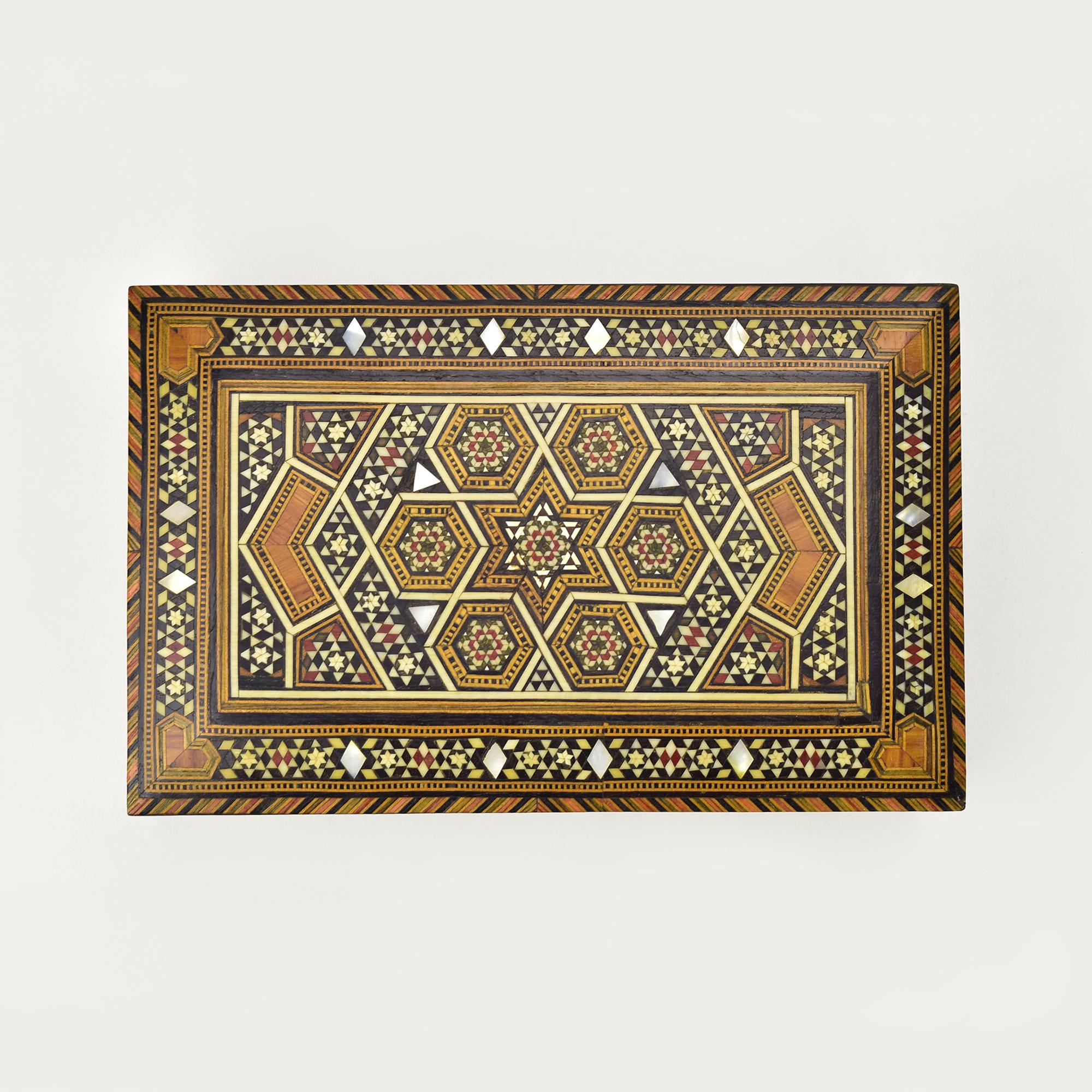 Il s'agit d'une boîte à bijoux de style mauresque ornée d'une marqueterie en mosaïque de motifs géométriques et floraux. Le design est très détaillé, avec de petites pièces de bois, de la nacre et d'autres matériaux méticuleusement arrangés pour