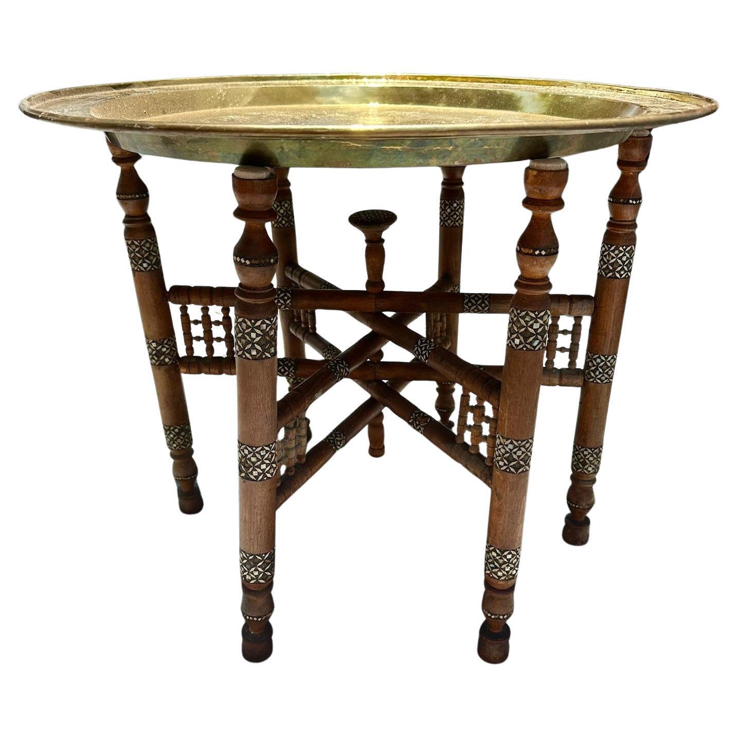 Moorish Inlaid Six-Legged Folding Side Table and Brass Tray Top.

The inlay work makes this folding tray an exceptional handmade side table. A hand carved turned wood base of 6 legs is ornately inlaid with Arabic inspired bone and mother of pearl