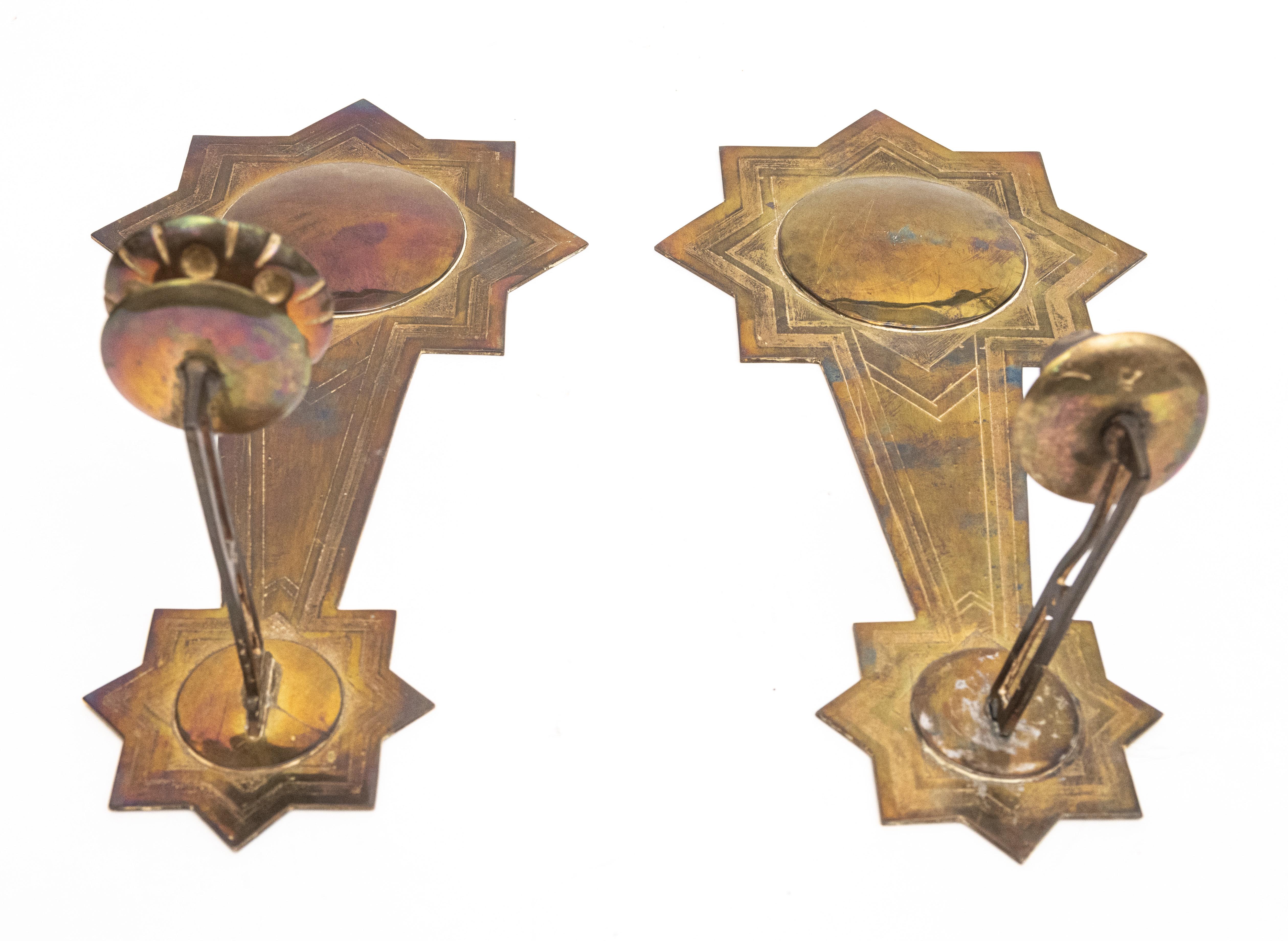 Paire d'appliques murales suédoises d'inspiration mauresque à une seule lumière, avec des plaques arrière bombées et des étoiles. Une coupelle à bougie unique dépasse d'un bras sur une plaque arrière travaillée à la main. Circa 1890