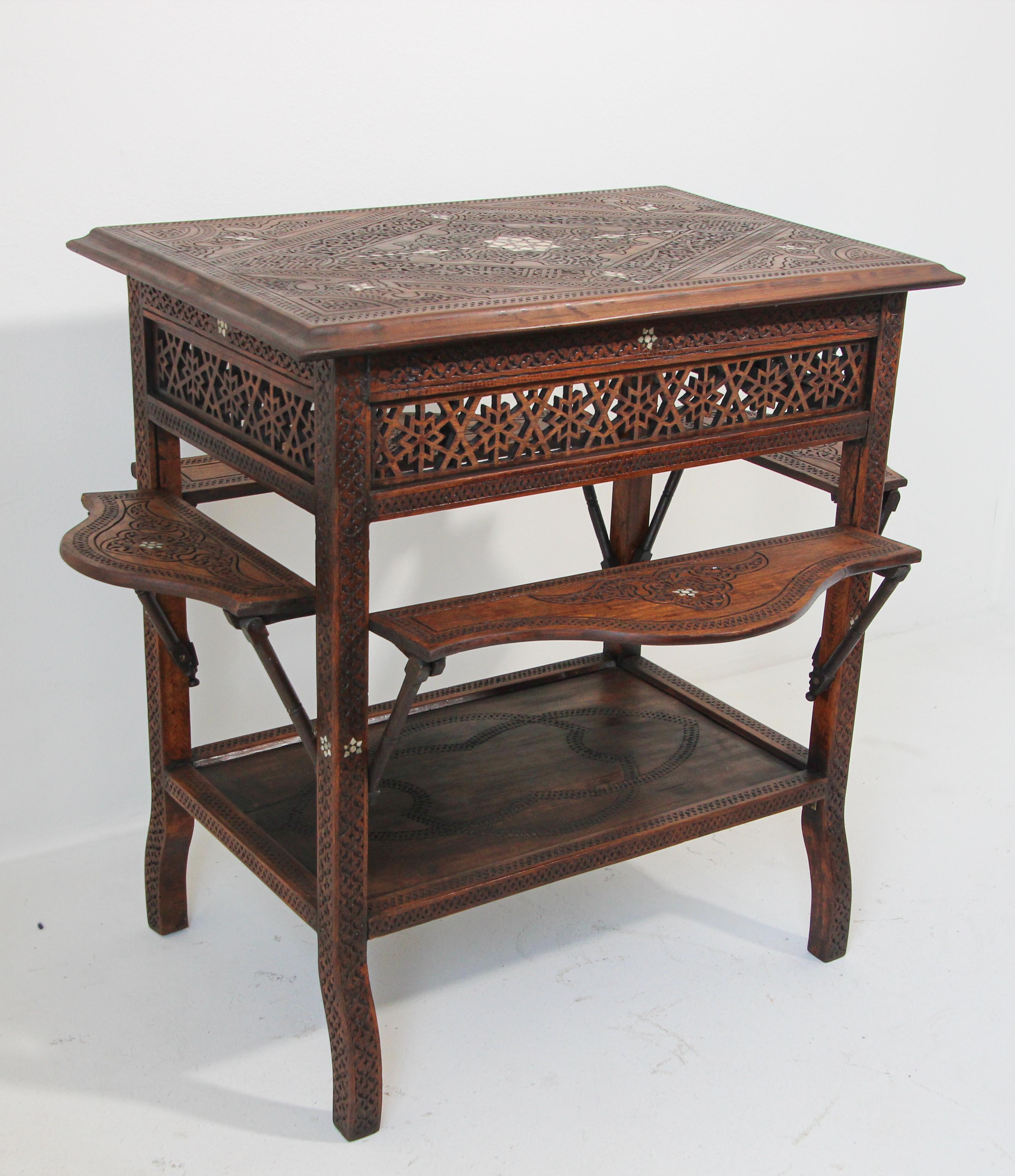 Moorish tea table, finely hand carved with foliages, arabesque design and Arabic writing, inlaid and carved in Moorish designs, 
The sides on the table folds and open for additional space. 
The border sides are made of fine fret work, called