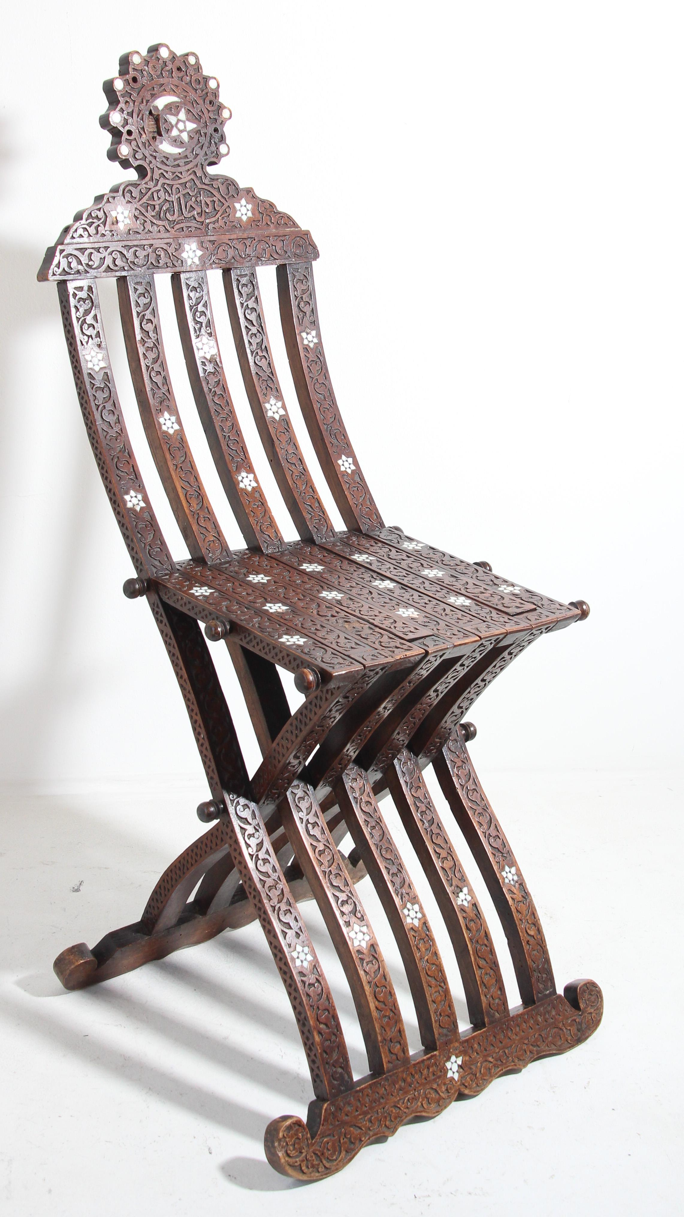 Antique Middle Eastern Moorish walnut wood folding chair with intricate foliate carving and mother of pearl, shell inlays.
Moroccan Moorish style folding chair inlaid with mother of pearl stars designs, hand carved with Arabic calligraphy script