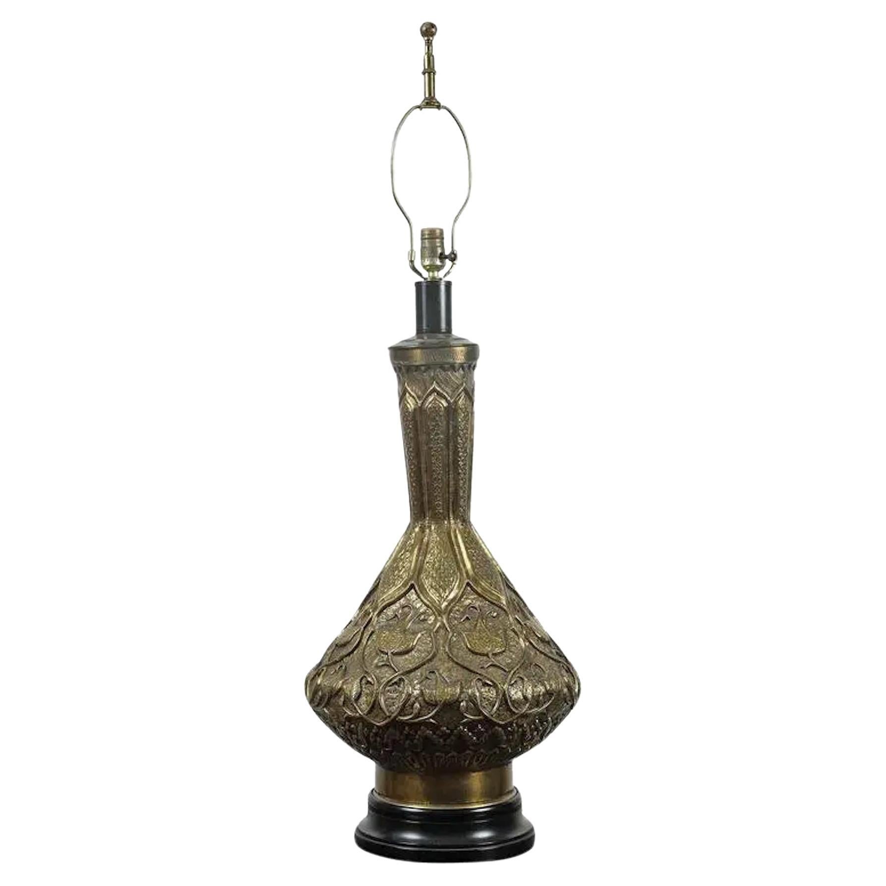 Large Indo Persian brass table lamp, finely embossed with Moorish repousse floral designs, sits on a black ebonized lacquered base.
Elegant intricate antique Indo-Persian hand-etched brass lidded urn mounted as a table lamp.
The brass harp has an