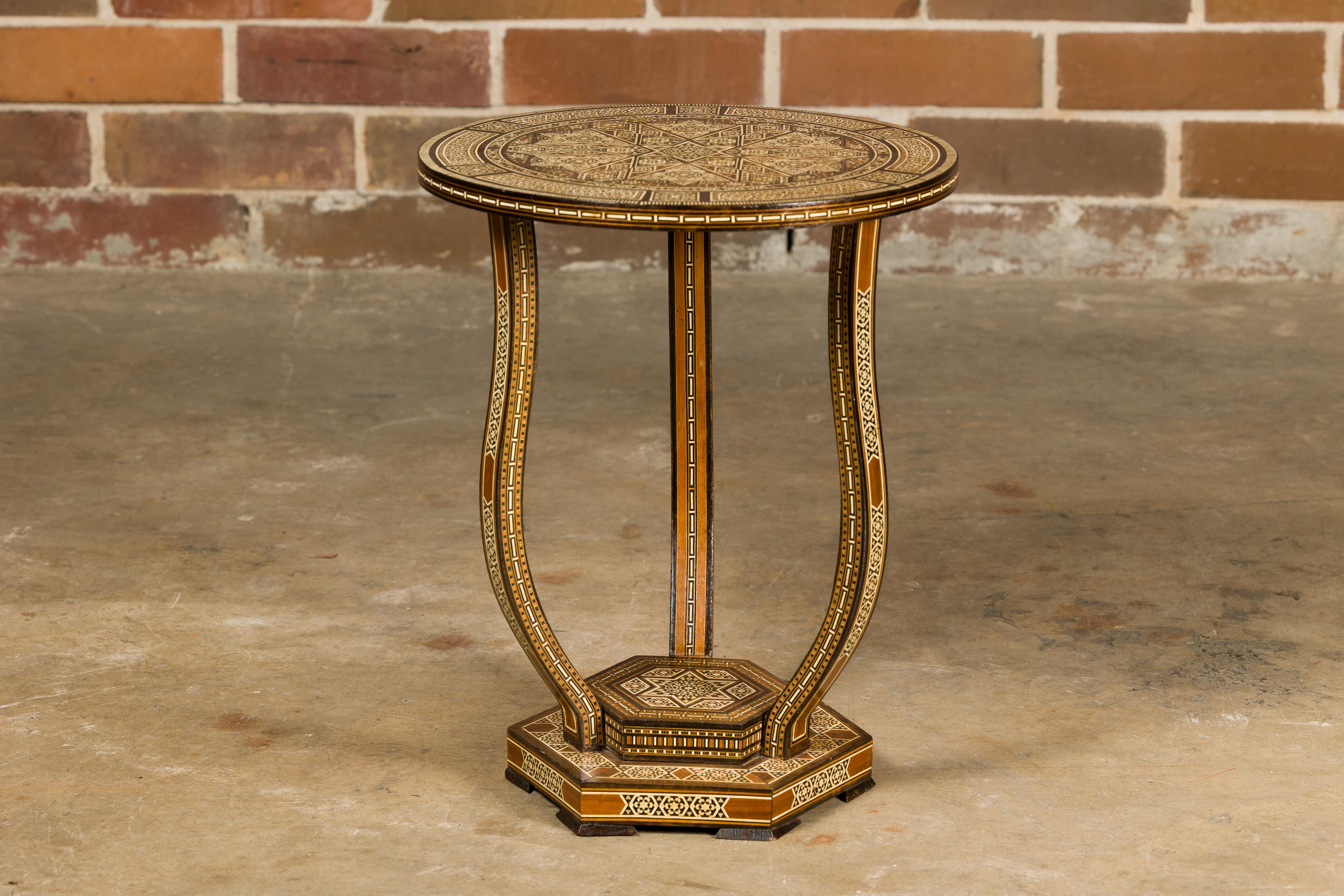 Table à boissons marocaine de style mauresque, datant d'environ 1900, avec plateau circulaire, abondante incrustation géométrique en os, trois pieds incurvés et une base hexagonale à gradins. Cette table à boissons marocaine de style mauresque
