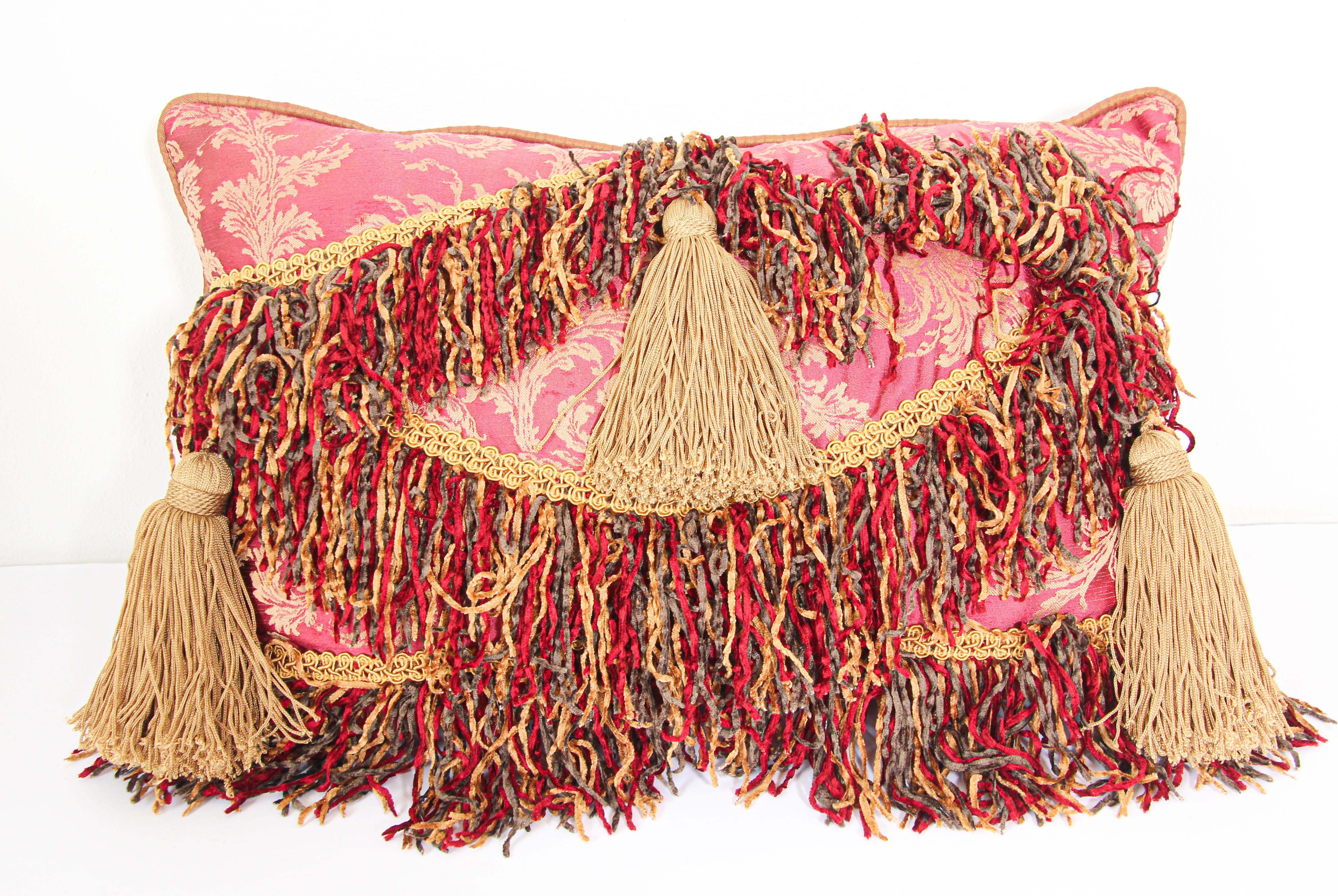 Middle Eastern Moorish style decorative throw pillow.
Luxury pillow in red, Pink and gold with an accent textile fragment in Venetian Fortuny style fabric in red and blue.
Decorative silk trim has been applied to finish the edges accented with