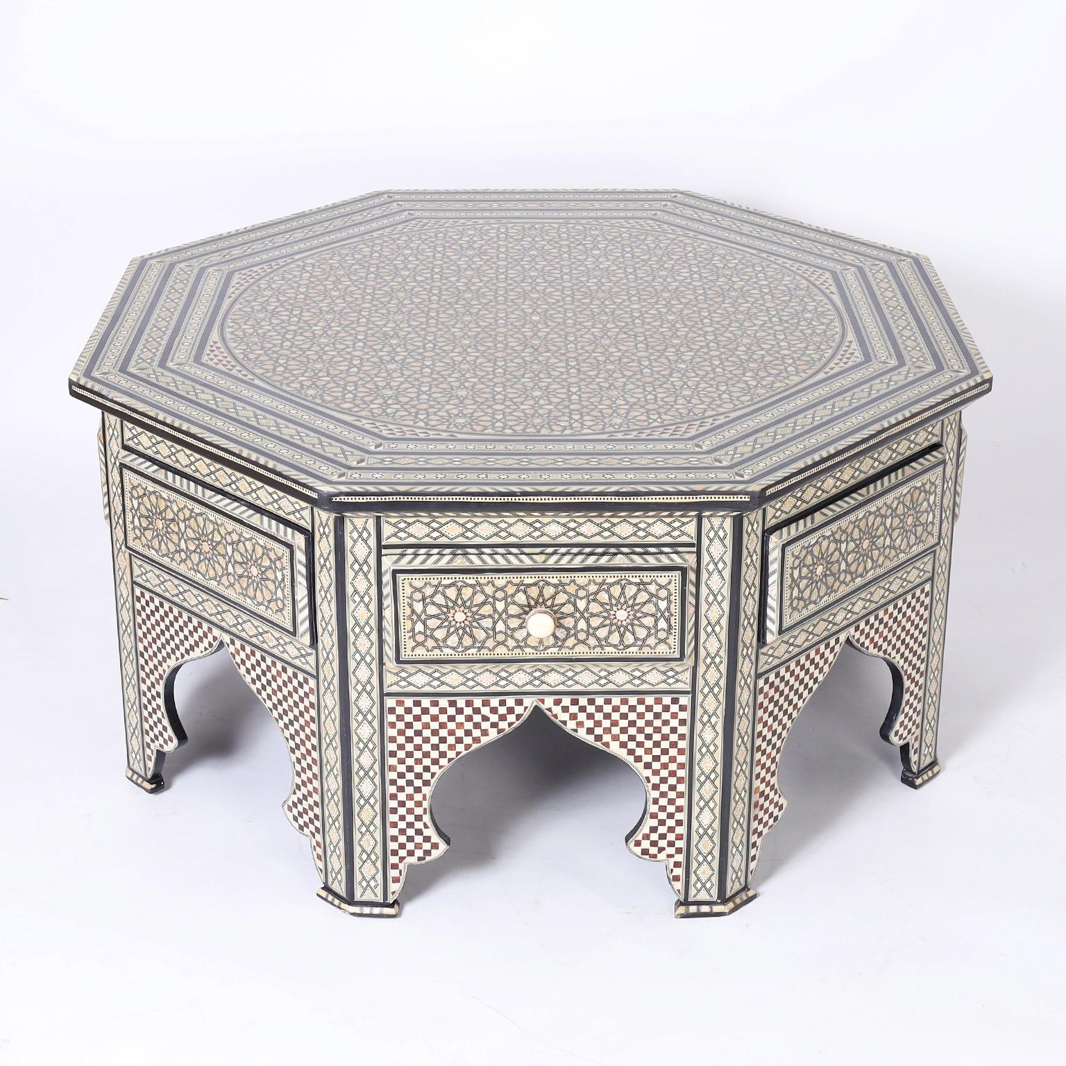 Vintage Moorish style coffee table with an octagon form featuring ambitious inlaid designs in mother of pearl, bone, ebony and mahogany, four drawers and a base with architectural arches.