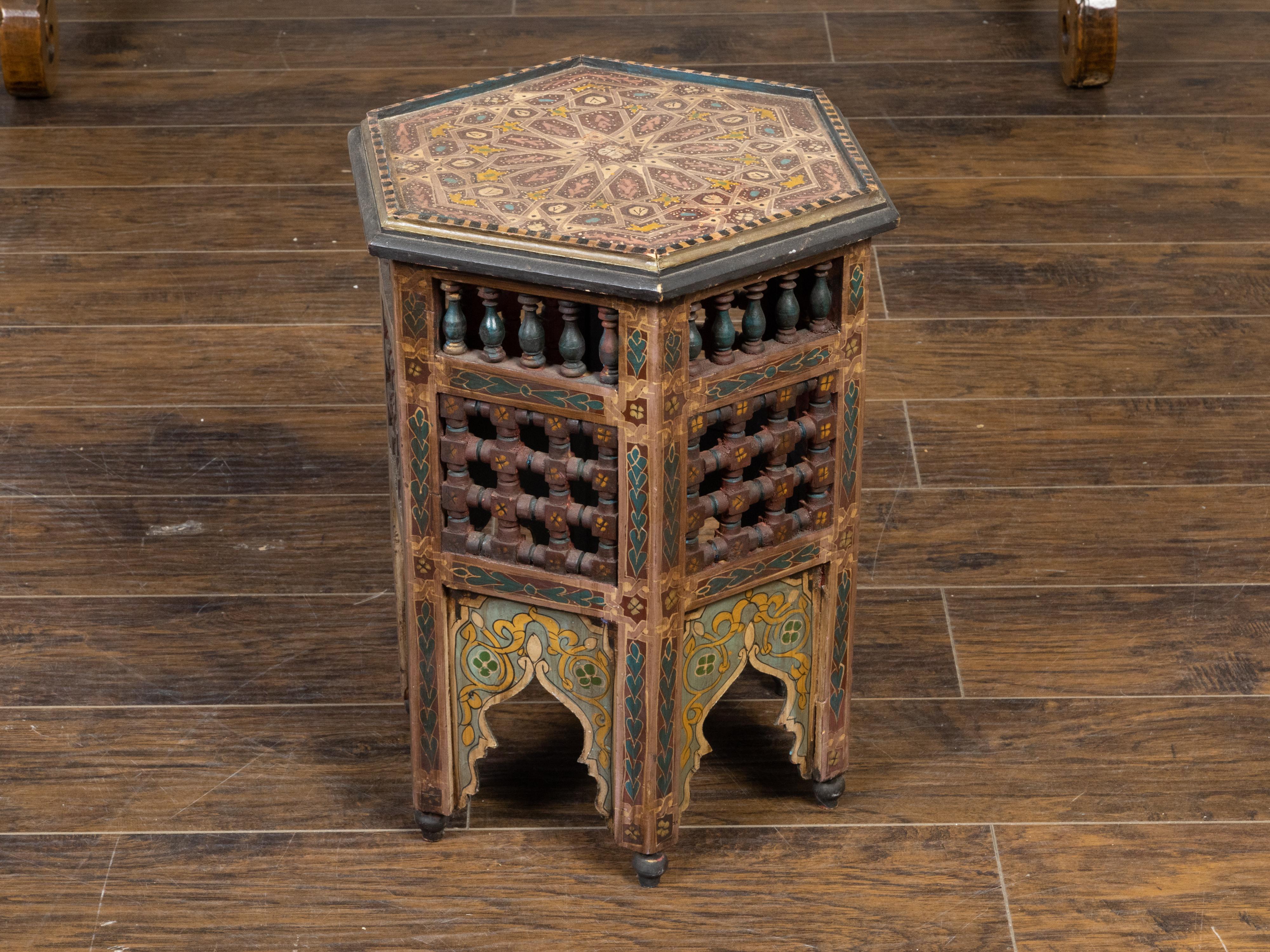A Moroccan Moorish style drinks table from the early 20th century, with painted geometric motifs, hexagonal top, polychrome décor, balusters and carved pierced motifs. Created in Morocco during the first quarter of the 20th century, this petite side