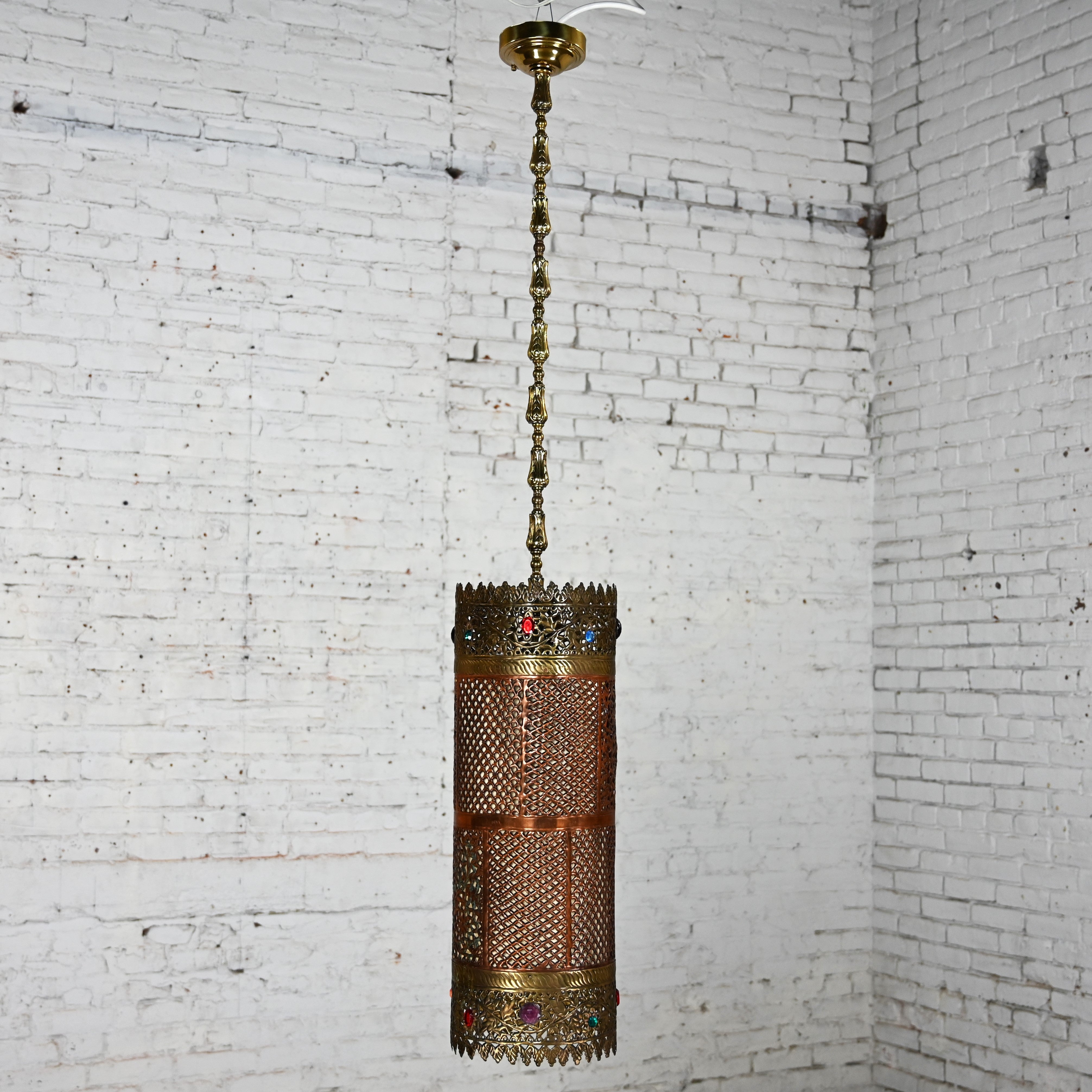 Magnificent vintage Moroccan or Moorish style embossed & pierced hand-crafted copper & brass pendant light fixture with multicolored glass & plastic jewels, decorative brass chain, and brass canopy, stamped Made in India. It is hardwired and has a