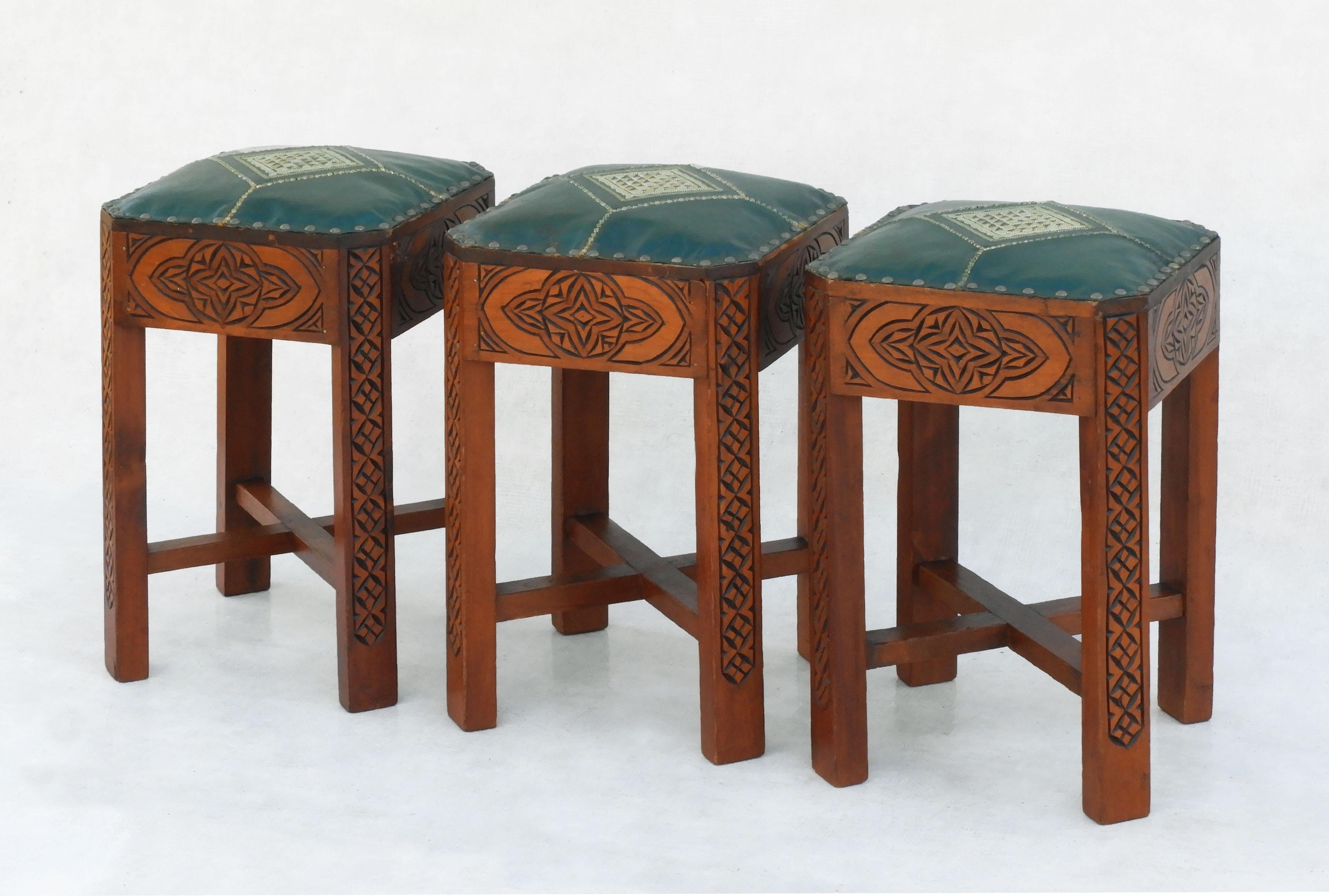 Unusual Moorish style tabouret stools C 1950s Morocco.  Hand-embroidered green leather upholstery, metal stud work and hand-carved decorative wood. In good vintage condition for their age, solid and sound with good patina.
Dimensions: Height: 46.5cm
