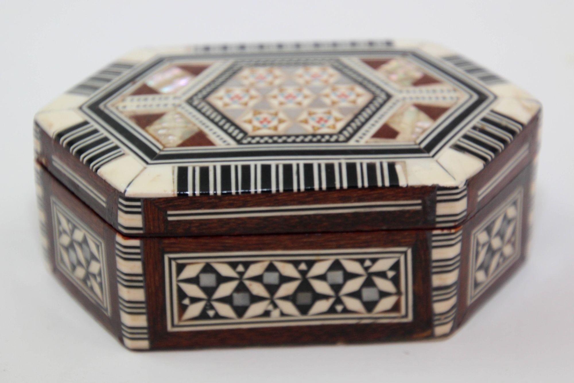Squisita scatola esagonale in legno con intarsio a mosaico del Medio Oriente realizzata a mano.
Scatola in noce di piccole dimensioni degli anni '50, decorata con motivi in madreperla bianca e vari legni pregiati di frutta che sono stati