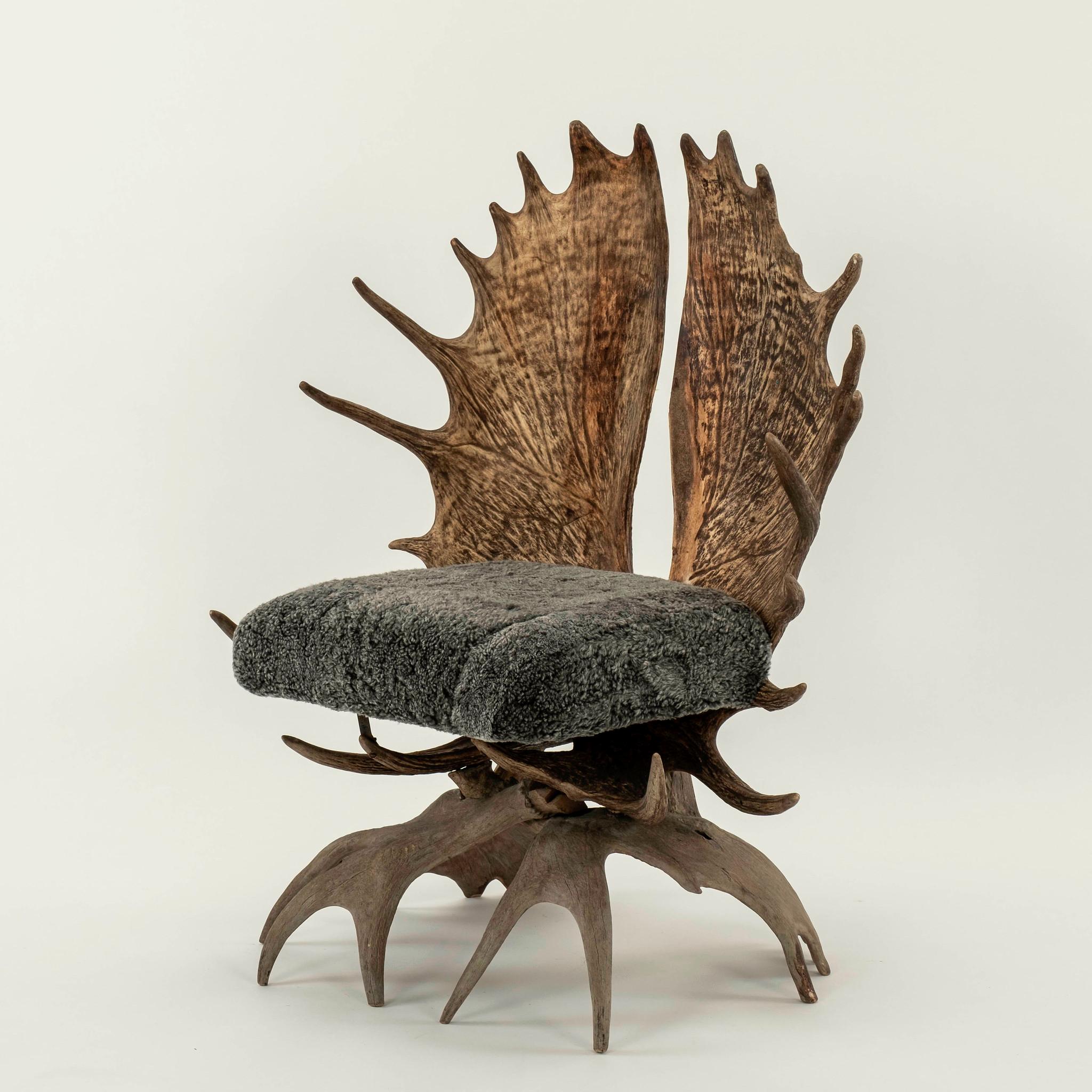 Early 20th Century handcrafted moose antler chair newly upholstered in a charcoal gray sheepskin.