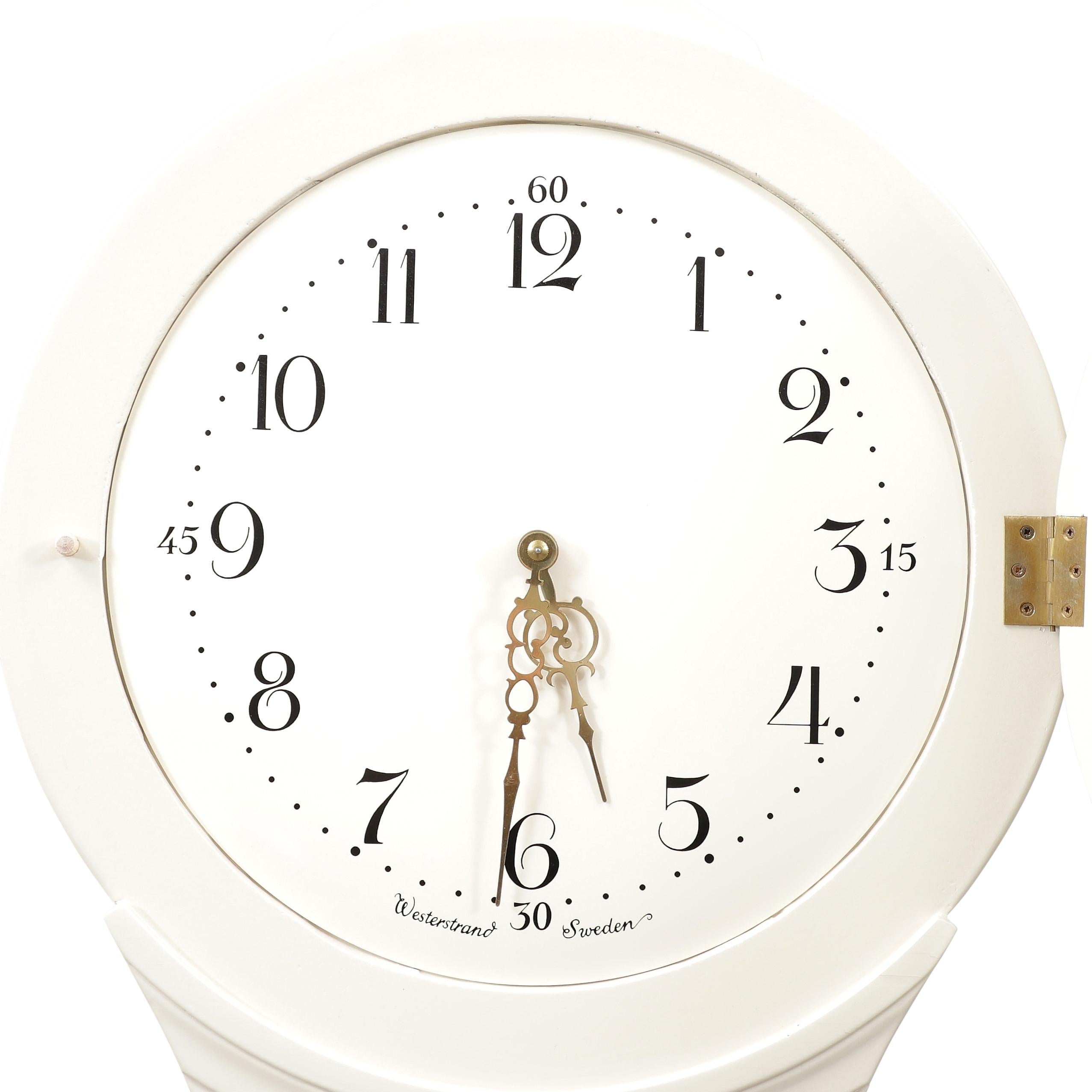 Horloge suédoise Mora des années 1900 avec des détails peints en crème et en or. La couronne est ornée de détails sculptés. Mécanisme d'horlogerie de type Longcase fonctionnant avec un pendule, deux poids et une cloche sonnant l'heure.

Largeur:52cm