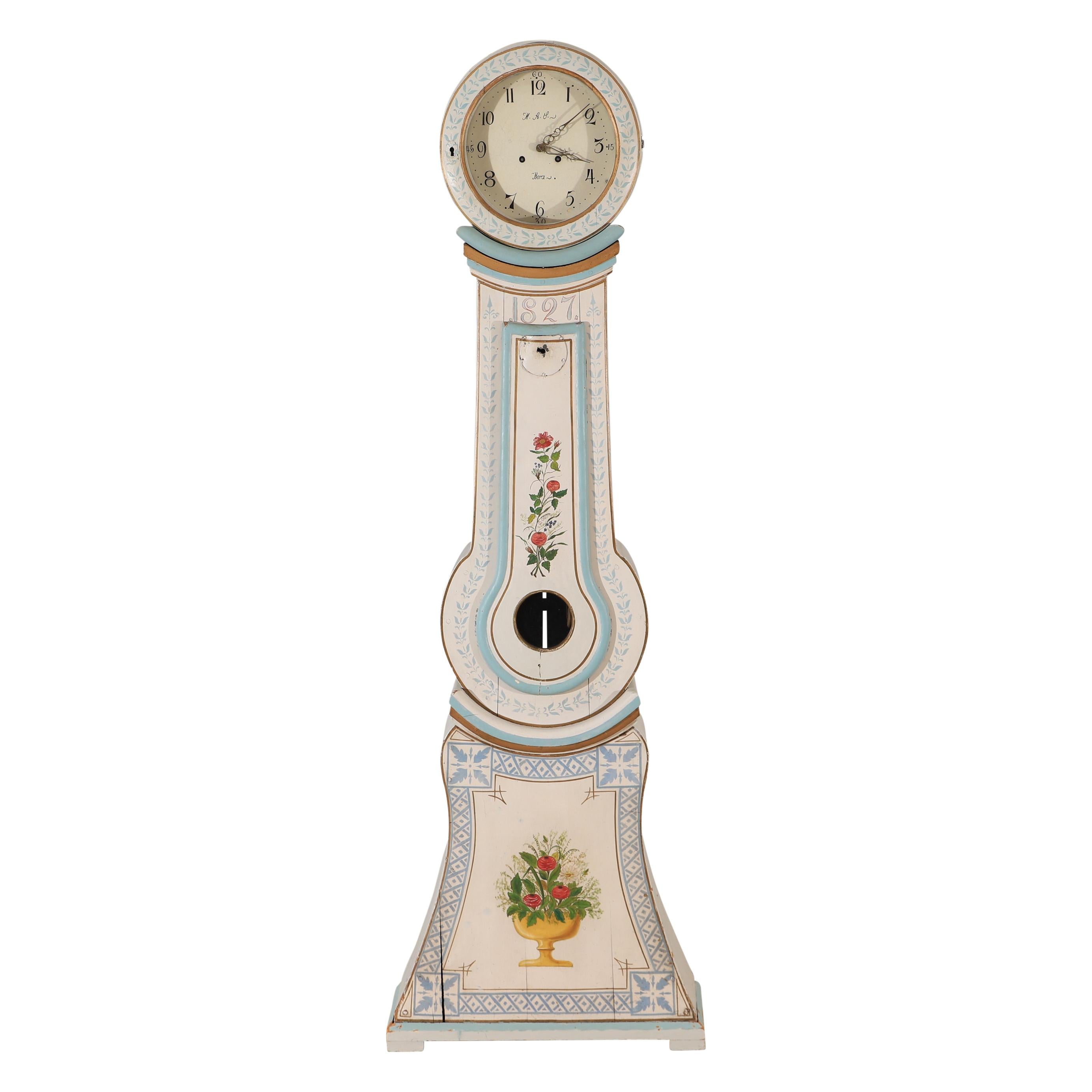 Antike schwedische Mora-Uhr, datiert 1827, mit dekorativen, gemalten Blumendetails. Zifferblatt mit den Initialen des Uhrmachers AAL und Mora. Originaler Mechanismus mit Gewichten und Pendel. Nicht funktionsgeprüft. 
Maße: Breite:68cm /