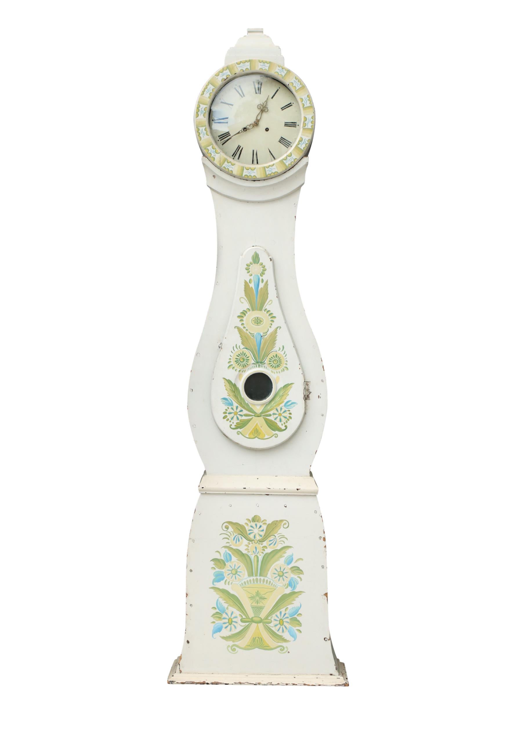 Horloge Mora suédoise des années 1800 avec des détails floraux peints à la main sur un fond peint en blanc (peinture d'origine). Couronne sculptée.  Mécanisme d'horlogerie de type Longcase fonctionnant avec un pendule, deux poids et une cloche