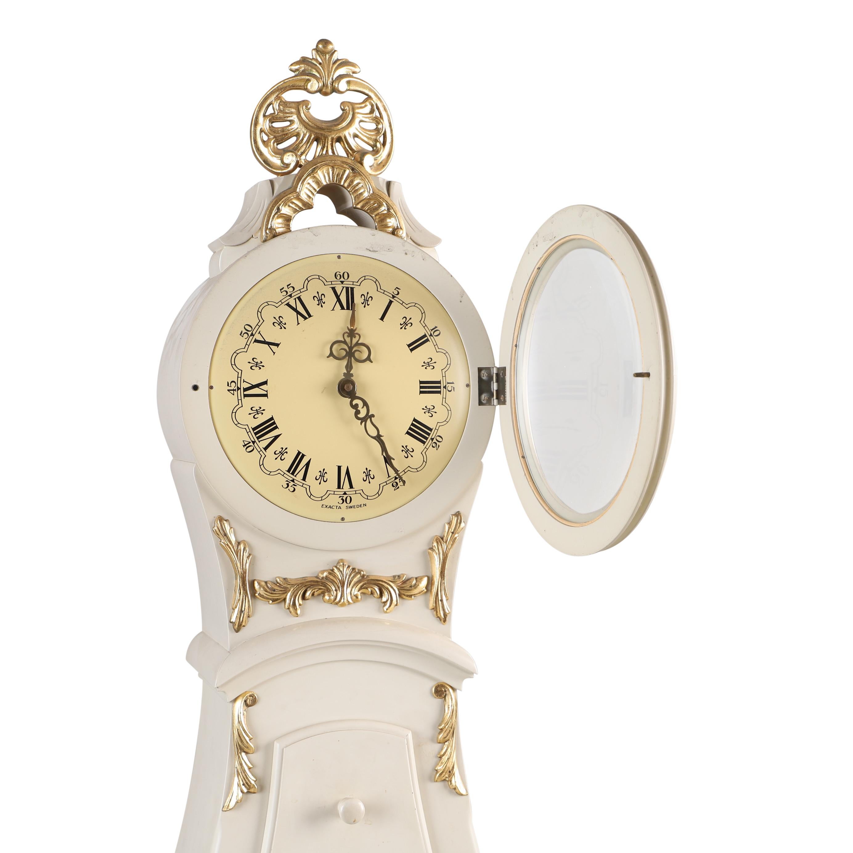 Swedish Mora clock from the 1960's in original colour. Cream with gold carved detailing. Working Longcase clock mechanism of pendulum and 2 weights and a bell chime on the hour.

Width:48cm / 18.9