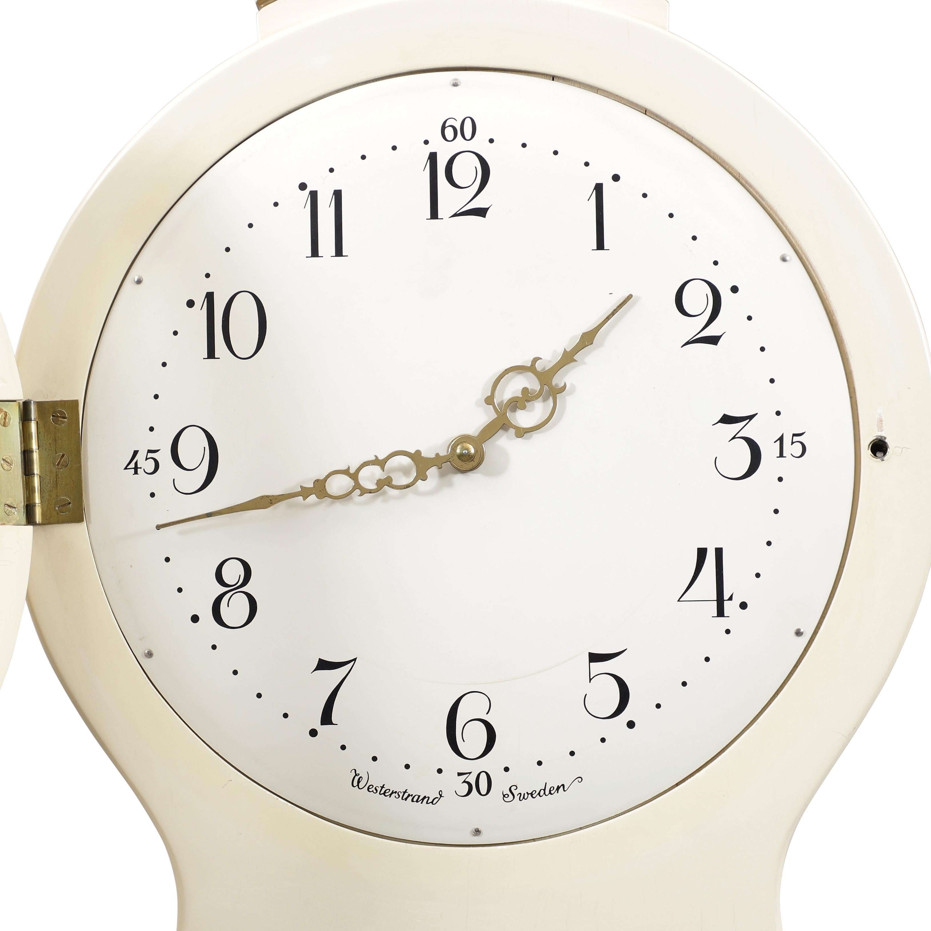 1900's Swedish Mora clock with cream and gold paint detailing. Carved detailing to crown. Working Longcase clock mechanism of pendulum and 2 weights and a bell chime on the hour.

Width:52cm / 20.4