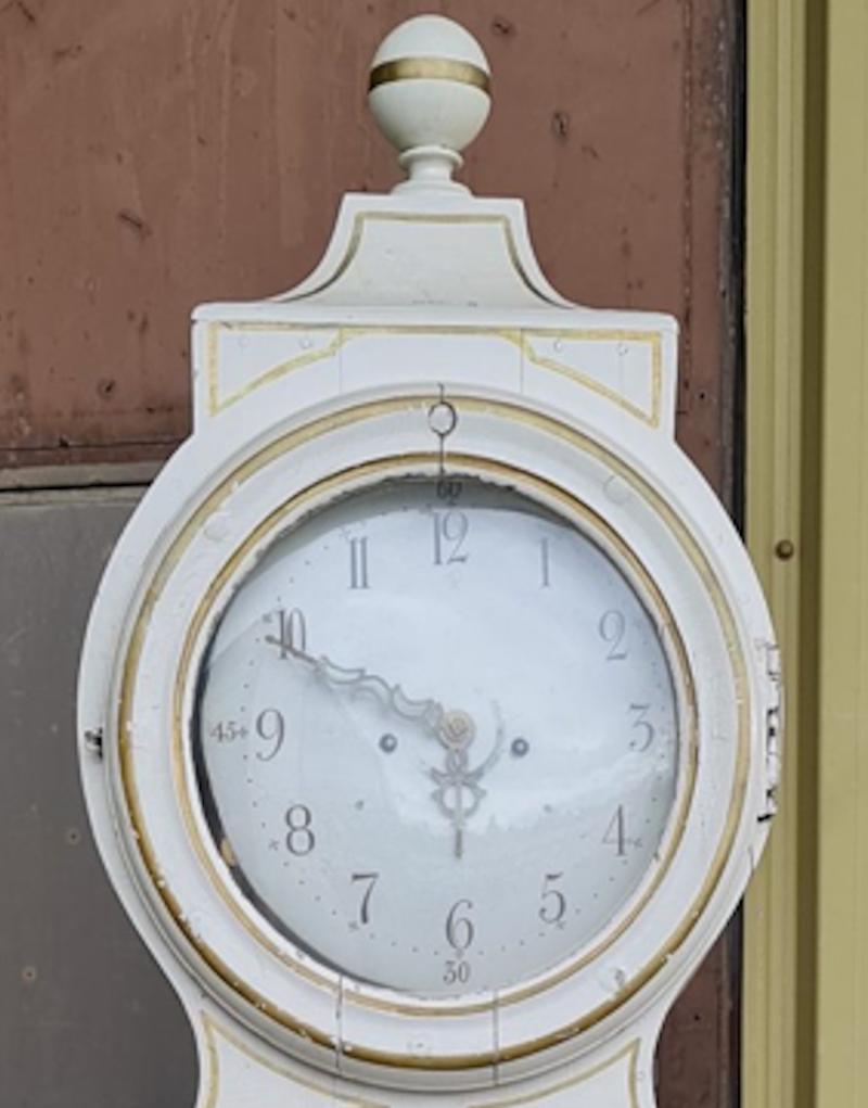 Antique Swedish mora clock from early 1800s Gustavian in white paint with gold detailing of great quality with lots of detail and nicely shaped hood.

It has the Classic extended belly of a traditional Swedish mora clock. Measures: 230cm tall