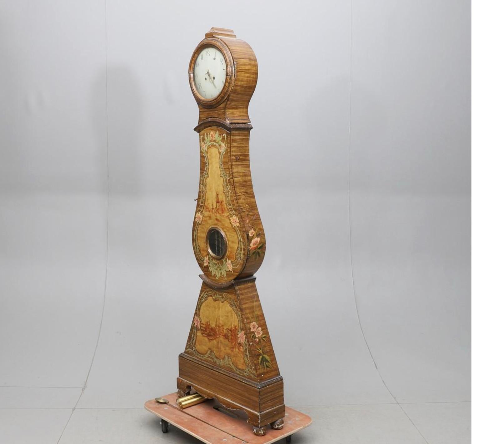 Antique Swedish mora clock from early 1800s Gustavian in possible original folk art paint of great quality showing a folk scene and a good face with lots of detail and nicely shaped hood.

It has the Classic extended belly of a traditional Swedish