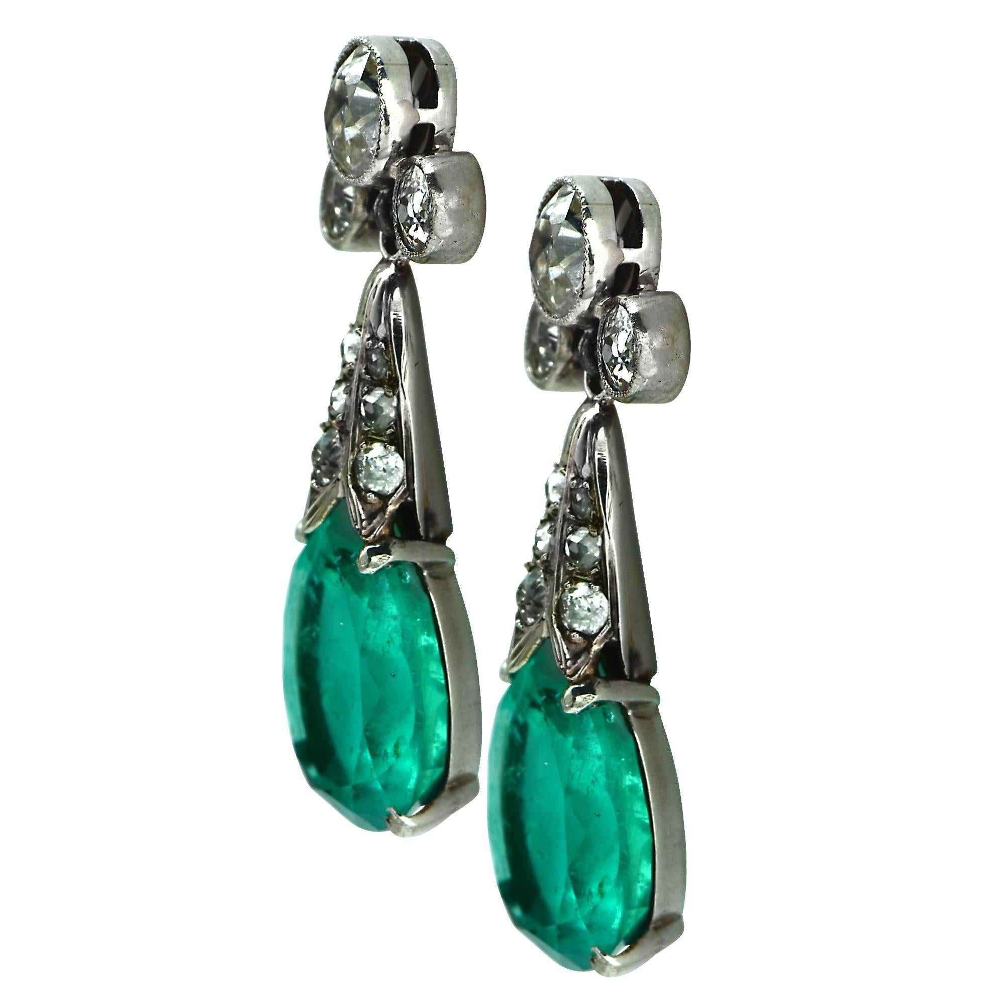Platinum modern Edwardian inspired dangle earrings featuring 2 pear shape Colombian emeralds weighing 9.84cts total. Accented by 24 European cut diamonds weighing approximately 3.20cts total, G-H color VS-SI clarity. The earrings measure 1.2 inches