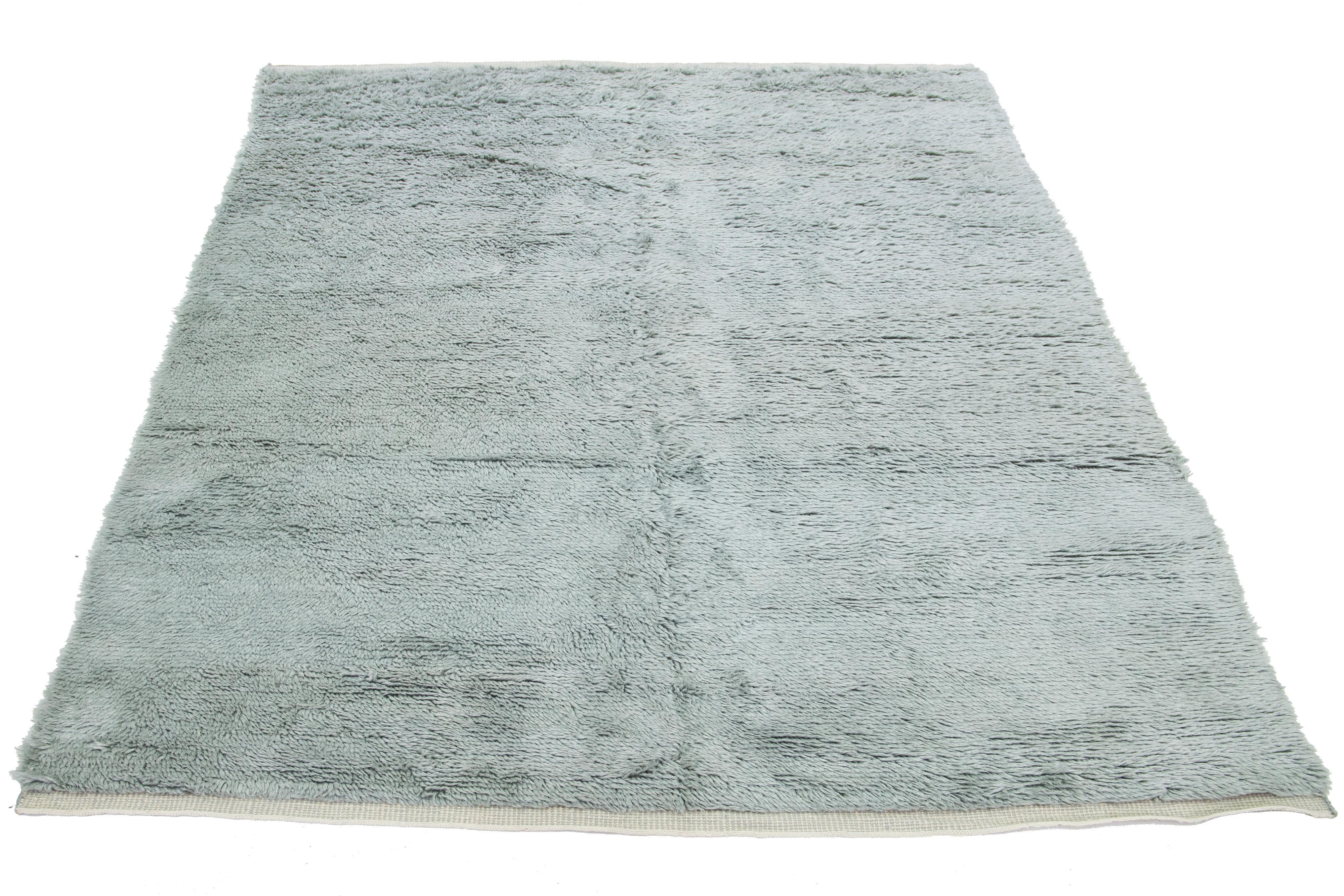 Questo tappeto in lana annodato a mano presenta uno stile marocchino Shag contemporaneo con un design solido e felpato e un campo grigio. Aggiunge un tocco accogliente all'arredamento.

Questo tappeto misura 7'10