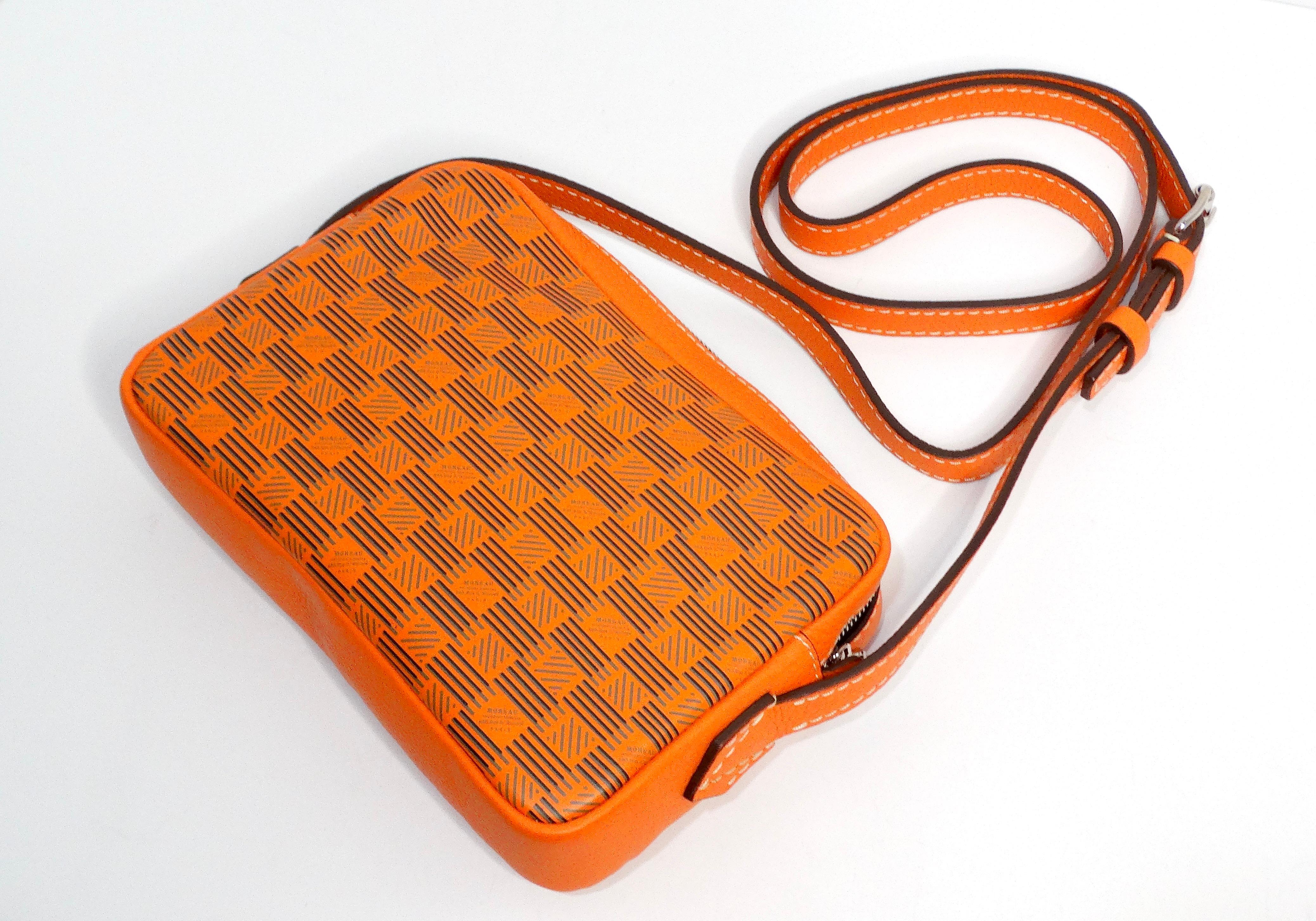 The Moreau Savoie Orange Monogram Leather Crossbody Bag is a stunning accessory that seamlessly blends functionality and style. Crafted from high-quality leather inside and out, this bag showcases a striking orange hue adorned with elegant white