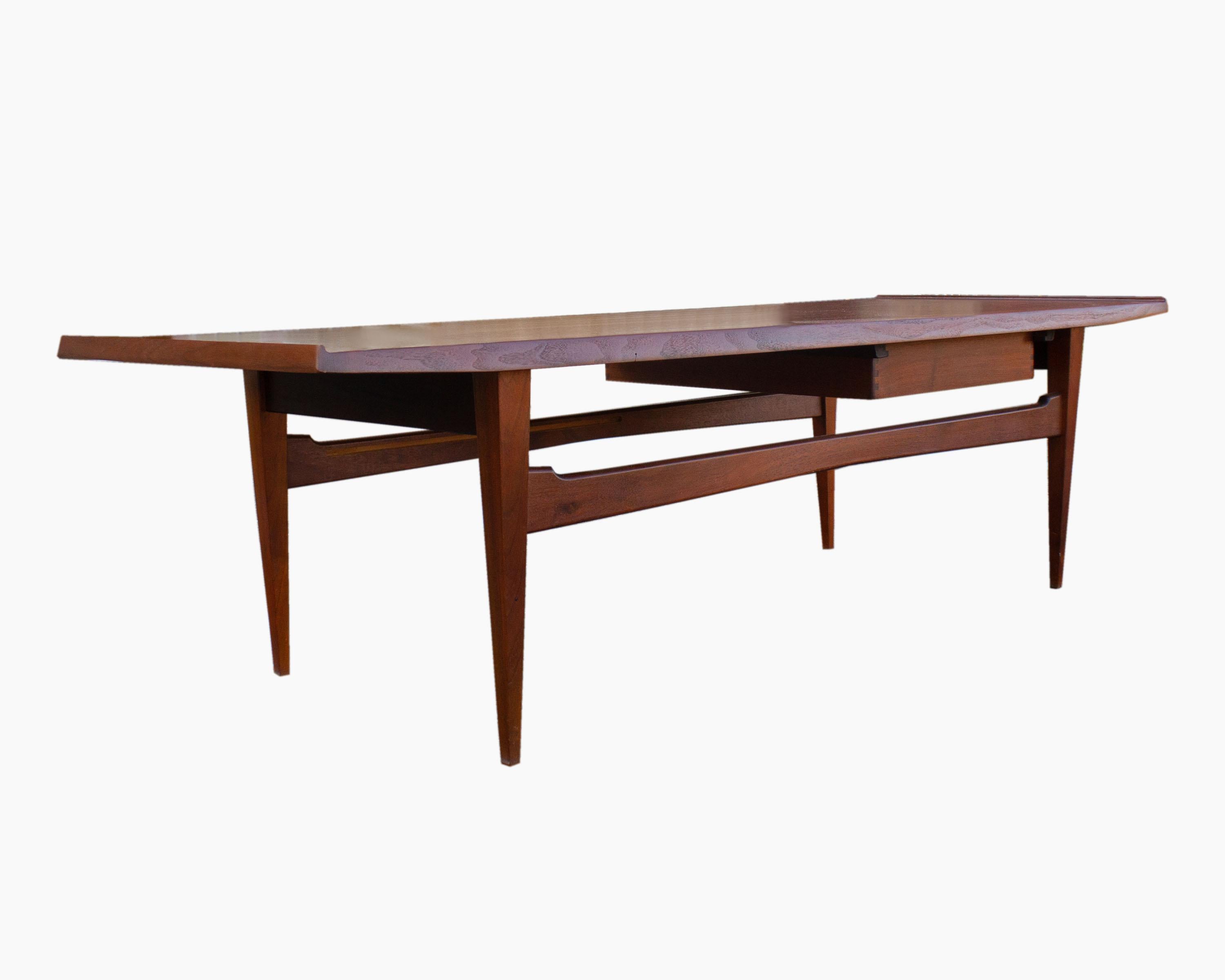 A Mid-Century Modern Danish coffee table manufactured by Moreddi Furniture Co. Composed of walnut and made in Denmark, the elongated table features a rectangular shape. Angled, slightly flared ends add visual interest to the sleek table top. Having