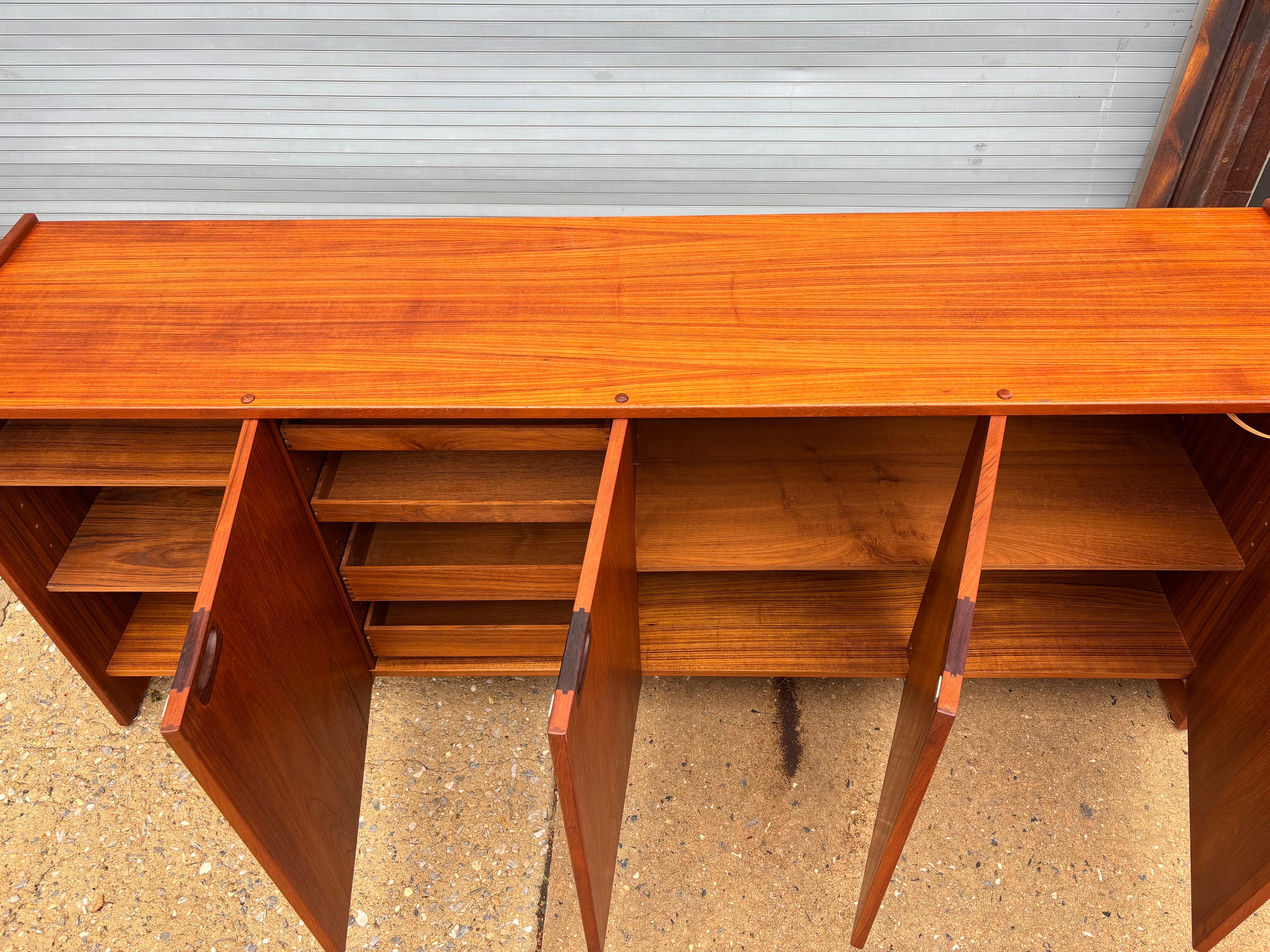 Moreddi 4 Door Buffet or Credenza.  Door open with a large wood dowel through the top surface.  Each handle is carved from solid Rosewood.  Doors open to reveal ample storage with pull out shallow drawers and adjustable shelves.  Top has been