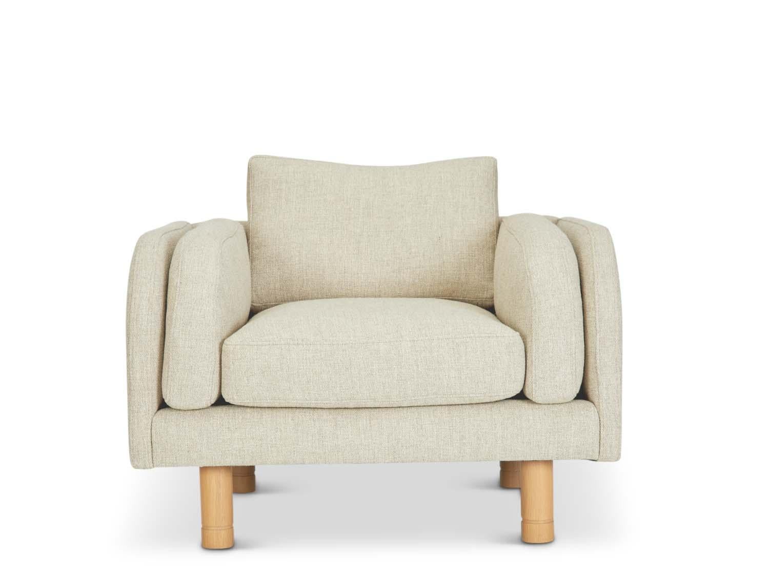 The Moreno chair sits low and deep with Italian-inspired curved arms. The chair features loose seat and back cushions and two side cushions that mimic the curvature of the arms. The legs have an incised detail and are made of solid American walnut