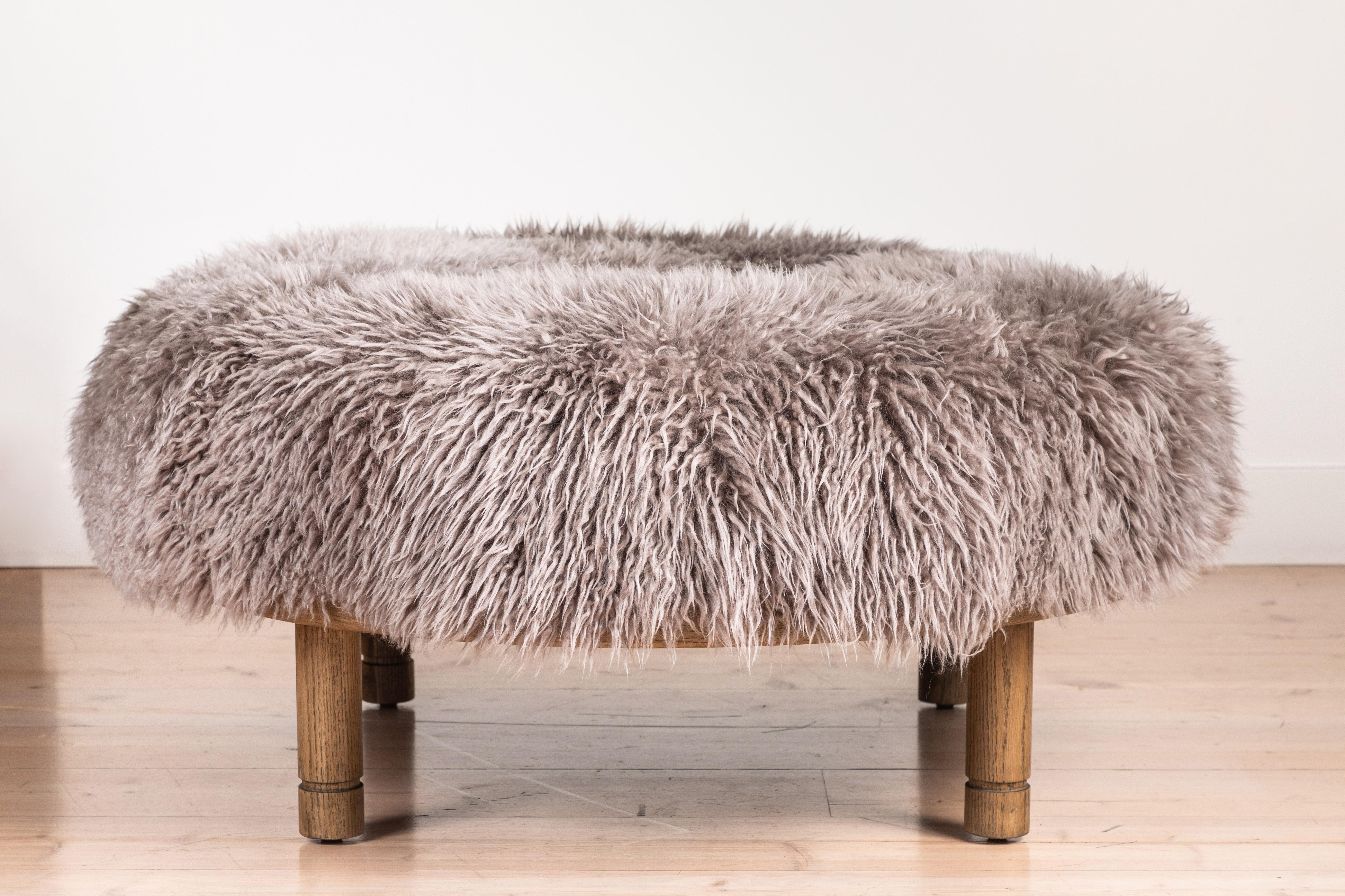 The Moreno Ottoman features a round solid wood base with four cylindrical legs and an upholstered top. Available in American walnut or white oak. Shown here in Smoked Oak and Garret Shearling. 

Available to order in Customer's Own Material with a