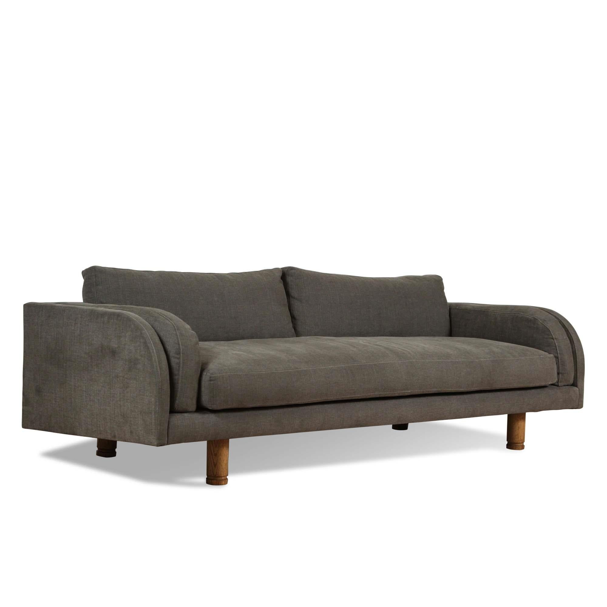 The Moreno sofa sits low and deep with Italian inspired curved arms. The sofa features loose seat and back cushions and two side cushions that mimic the curvature of the arms. The legs have an incised detail and are made of solid American walnut or