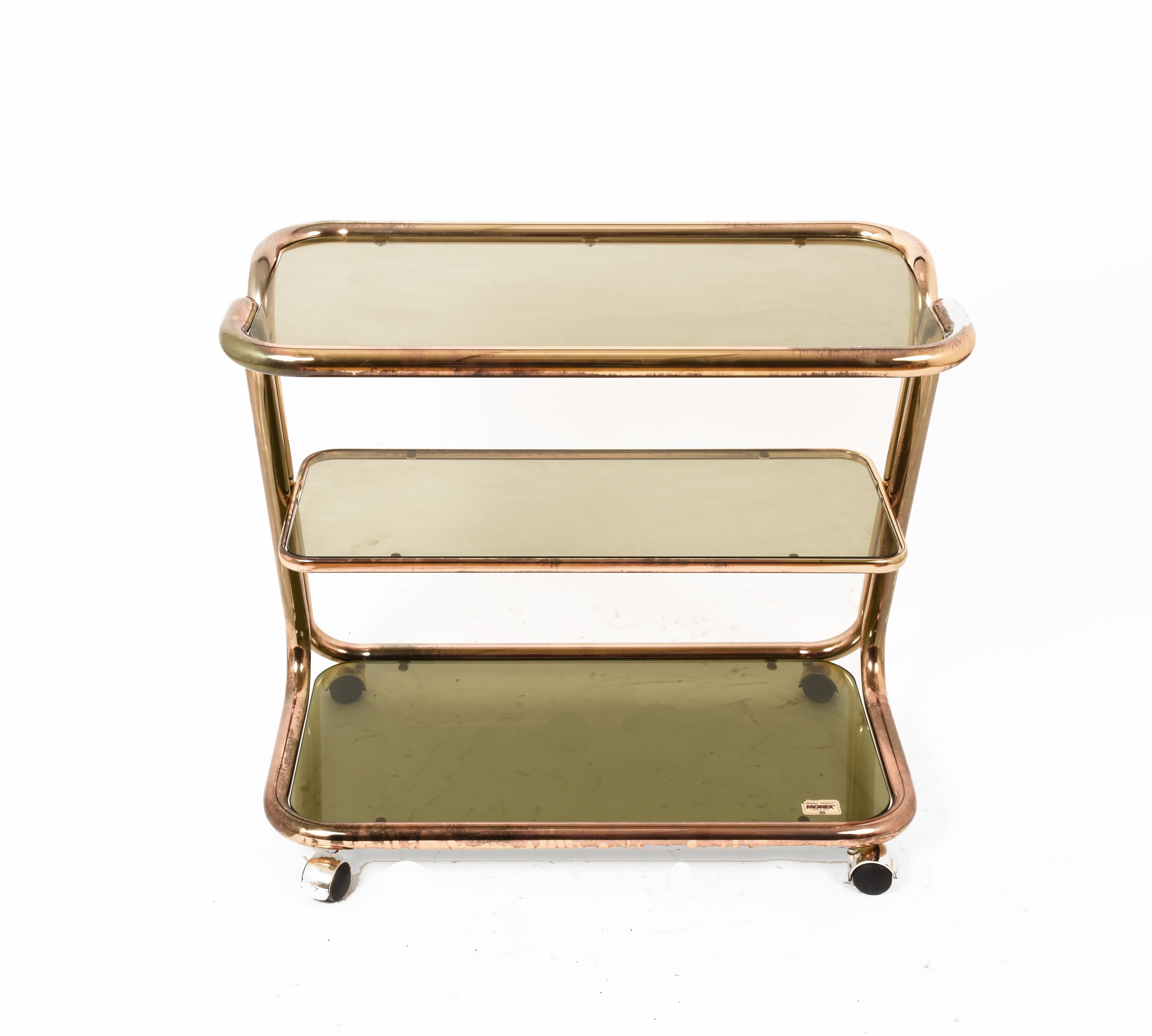 Exceptional midcentury brass and smoked glass bar cart on three levels. This three-level service cart was produced by Morex in Italy during 1970s.

The elegance of this wonderful piece is due to the tubular, delicate brass structure and the olive