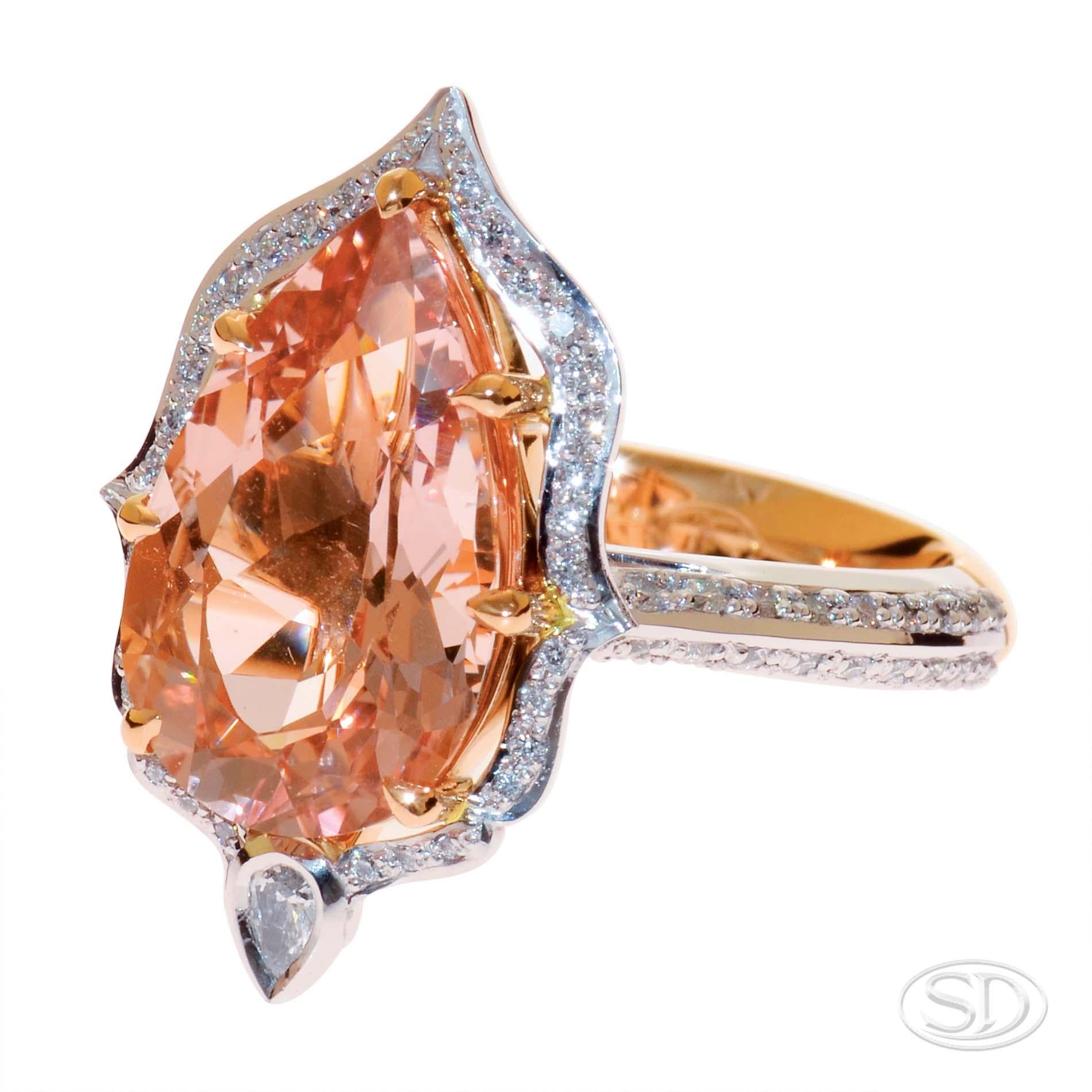 The morganite is 4.86ct and it is haloed in grain set diamonds.  This unusual shaped halo is called a fancy-shaped halo.  The band is bevelled & grain set with diamonds. There is a bezel-set 0.06ct pear shaped diamond at the base of the morganite