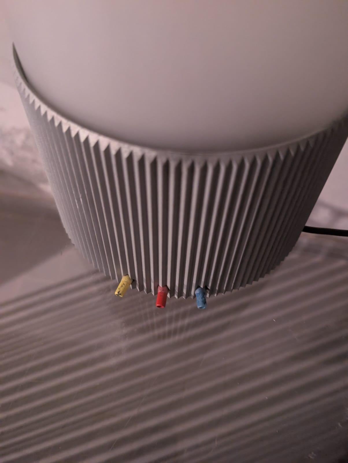 The Morgana low-tension table lamp has multi-coloured light stream provided by 3 cloloured bulbs (yellow, red, blue). The lamp base is made of grey-painted die-cast aluminium, while the lamp diffuser is made of etched blown glass. The Morgana model,