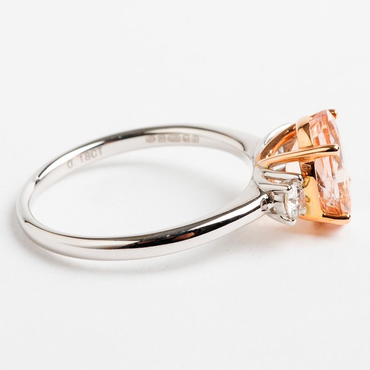 A uniquely designed piece, our ring features a prominent est. 1.57carat oval shaped morganite in a rose gold baser with two round brilliant cut diamonds on either side (est .18carat), on a 18k white gold shank. Hallmarked London 2019, the ring size