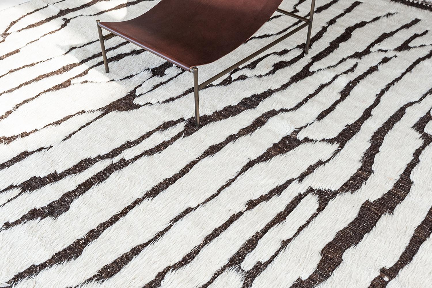 Grazie alla sua semplicità, questo tappeto dal design Moringa color antracite della nostra collezione Atlas renderà il tuo spazio più elegante. I bordi a coda di pesce con bordi superiori e inferiori in marrone pieno in un campo di crema rendono il