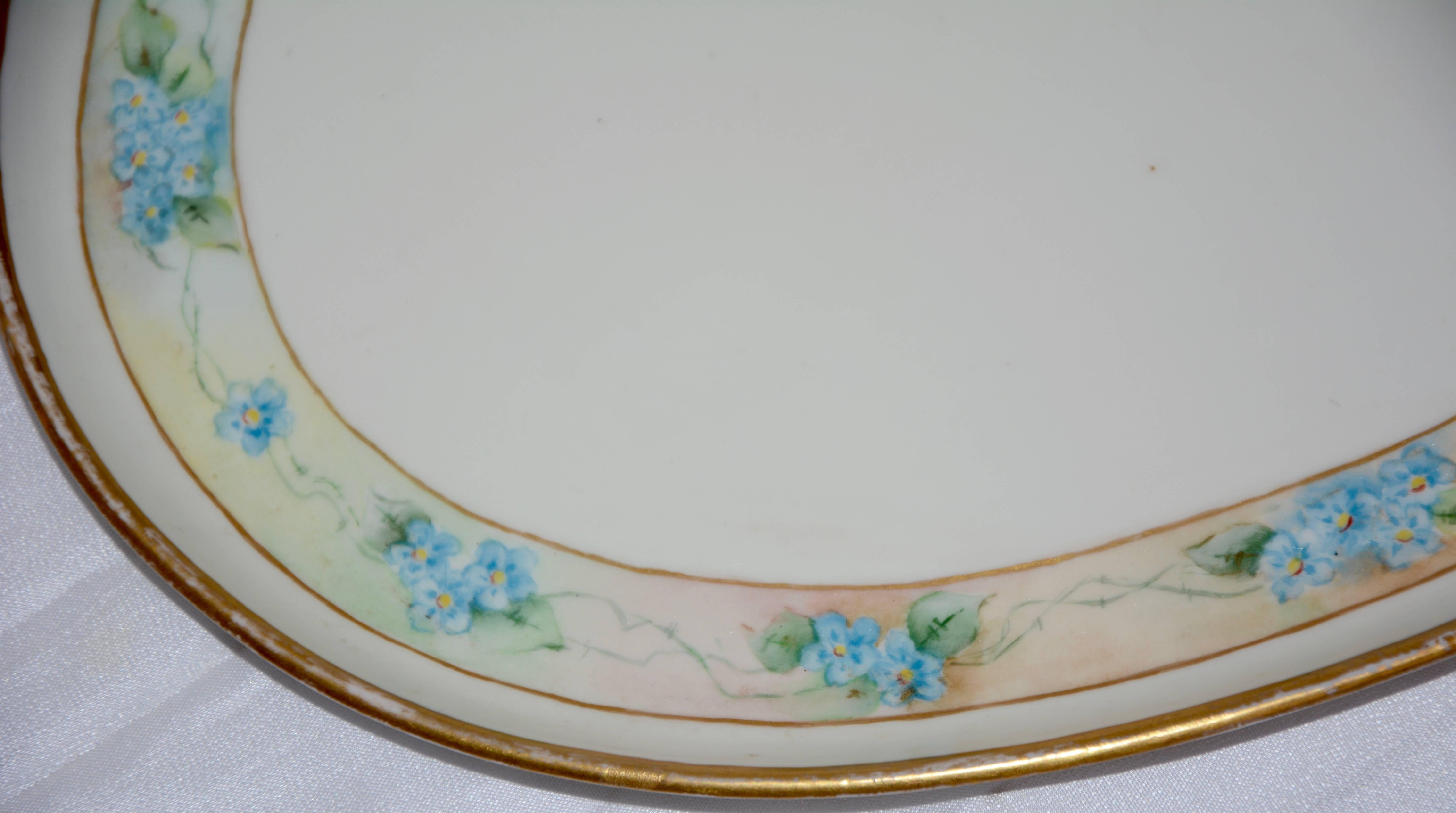 Dainty blue flowers surround the edges of this porcelain platter by Moritz Zdekauer of Austria. The flower garland is bordered in gold as well as the rim. The platter is marked on the back with the M K mark Austria and has been signed by the artist,