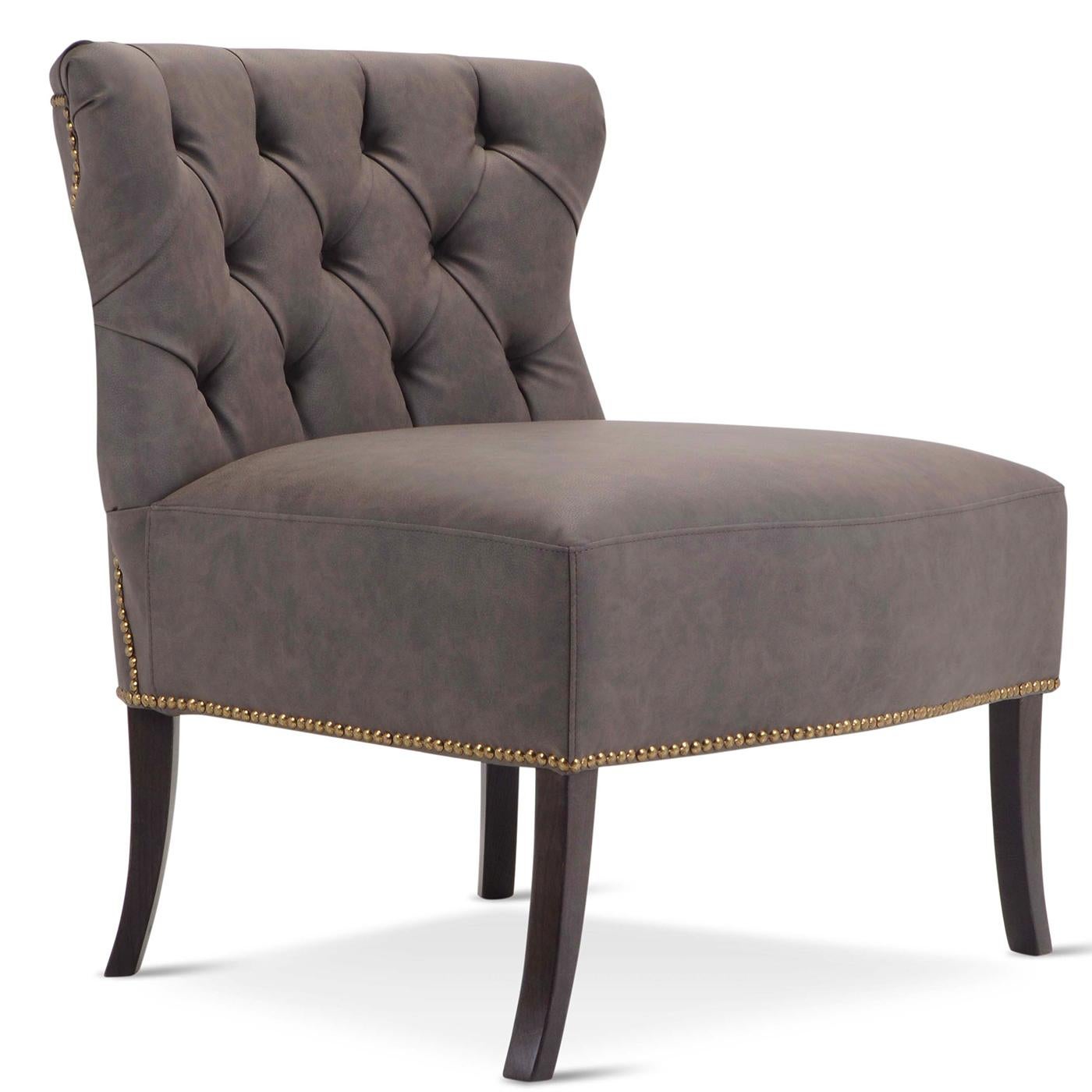 Classic and refined, this armchair boasts a generous silhouette with a broad tufted back and a square seat cushion supported by Saber-style wooden legs with a black finish. Upholstered in dark gray Dacron, the plywood frame is padded with