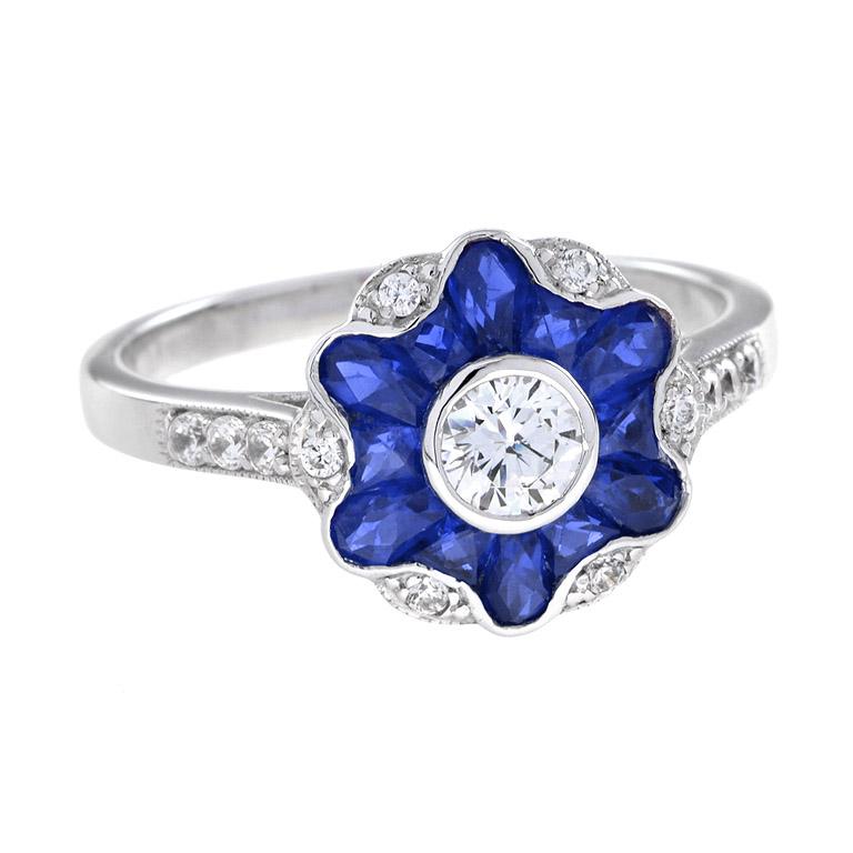 With a gorgeous design that includes a diamond center and sapphire petals of morning glory flower design, this art deco style ring will make you beam with happiness. 14K White Gold. 
Ring Information
Style: Art Deco
Weight: 4.00 g. (approx. total