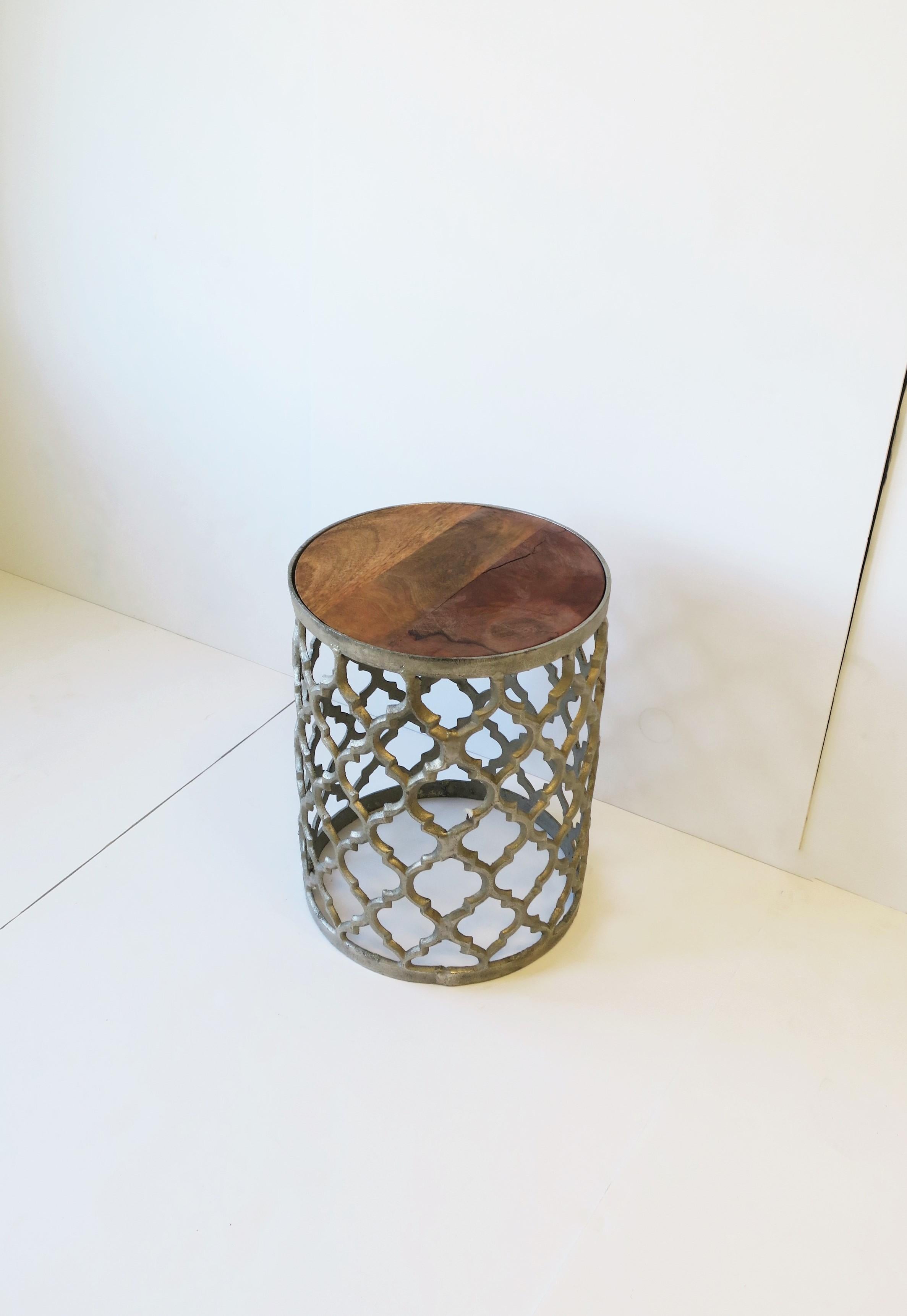 A silvered metal round drinks or side table with a Moorish design style, circa early 21st century. A silver-tone metal drinks, side, or end table with a Moroccan/Moorish designed base frame and tri-tone wood top. A convenient table that easy to move