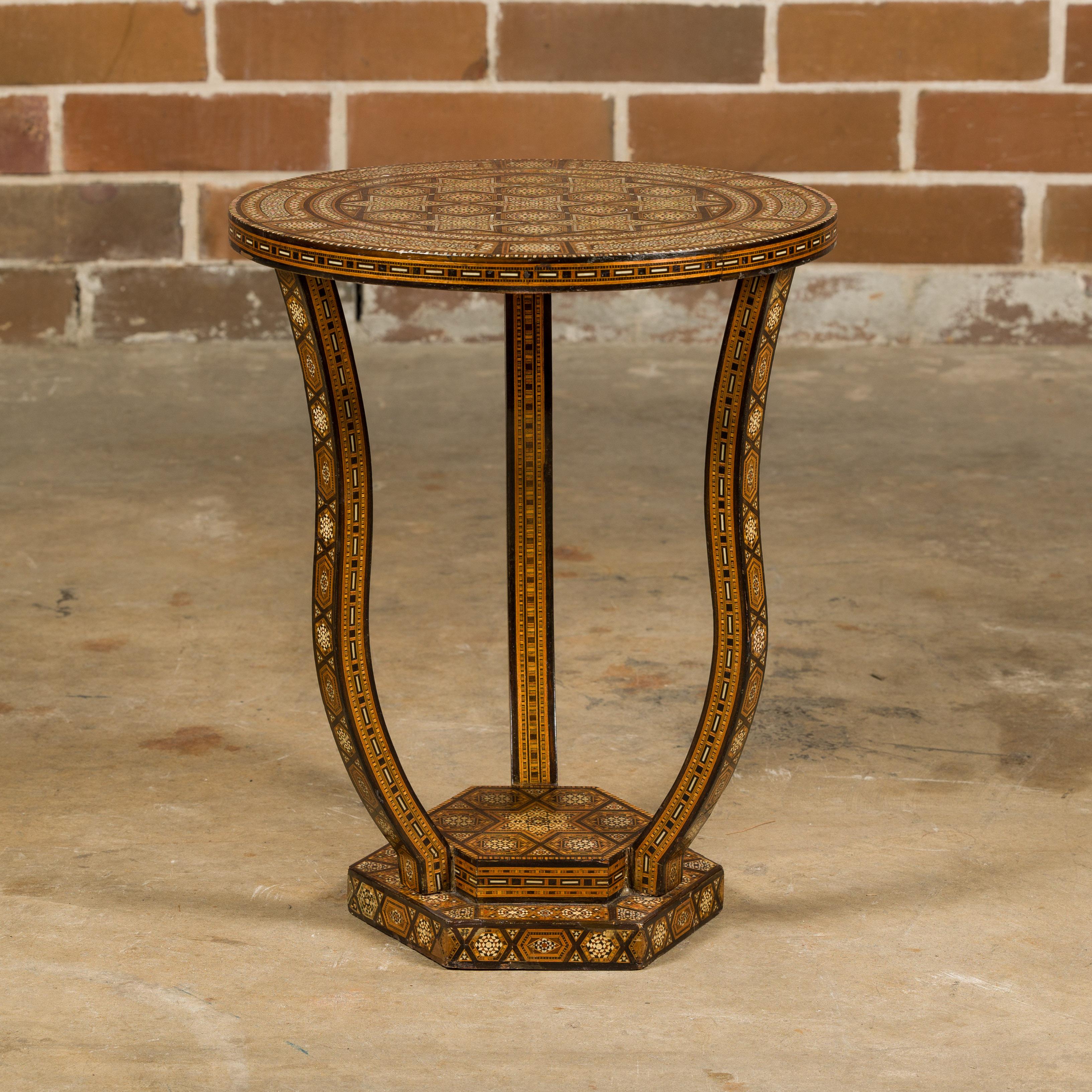 A Moorish style Moroccan drinks table from circa 1900 with circular top, abundant geometric bone inlay, three curving legs and stepped hexagonal base. This exquisite Moorish-style Moroccan drinks table from circa 1900 is a testament to the intricate